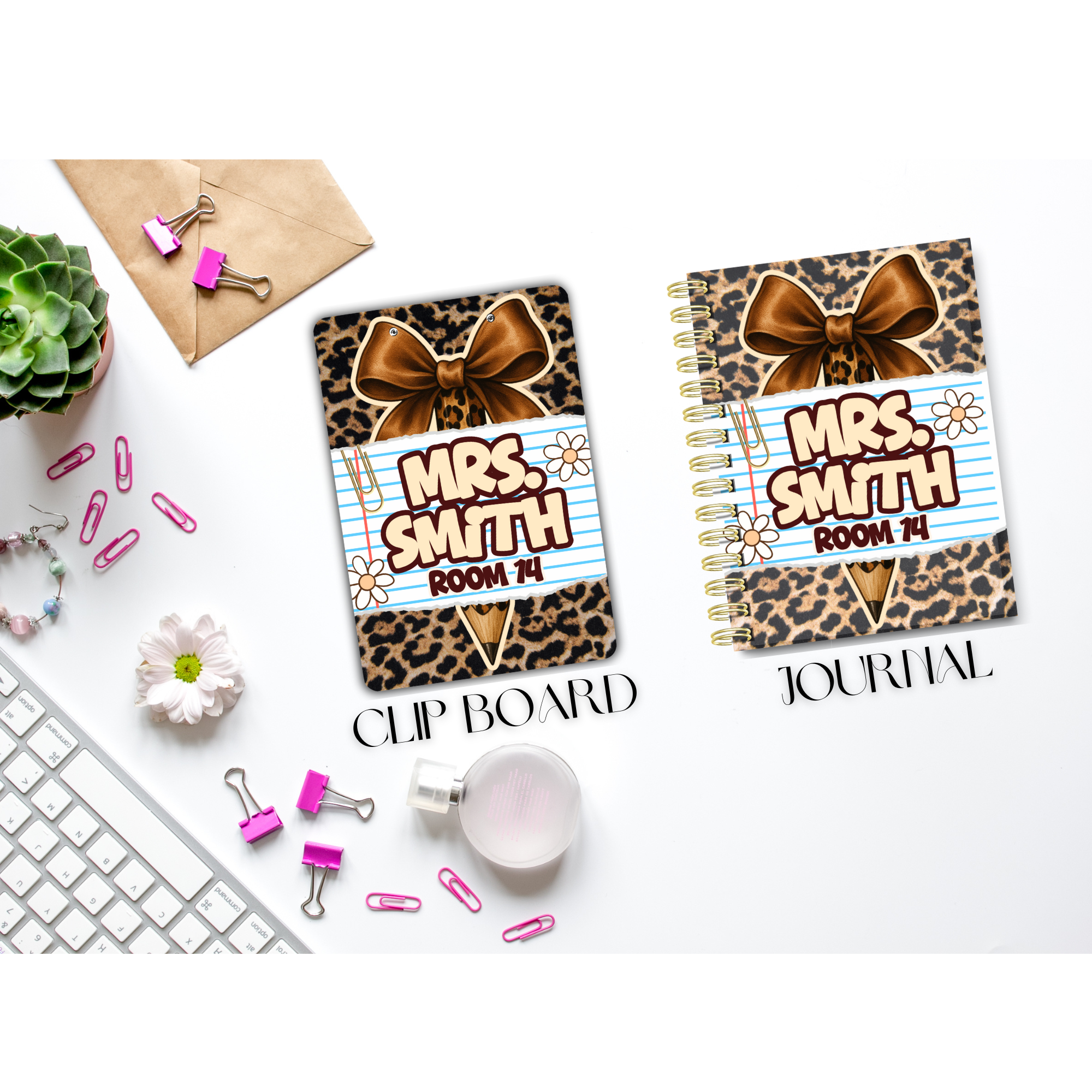 Desk with a plant, pink paper clips, a bracelet, a white computer keyboard, a small bottle, and two school supplies labeled 'Mrs. Smith Room 14' - a clip board and a spiral notebook, both with leopard print and a bow design.