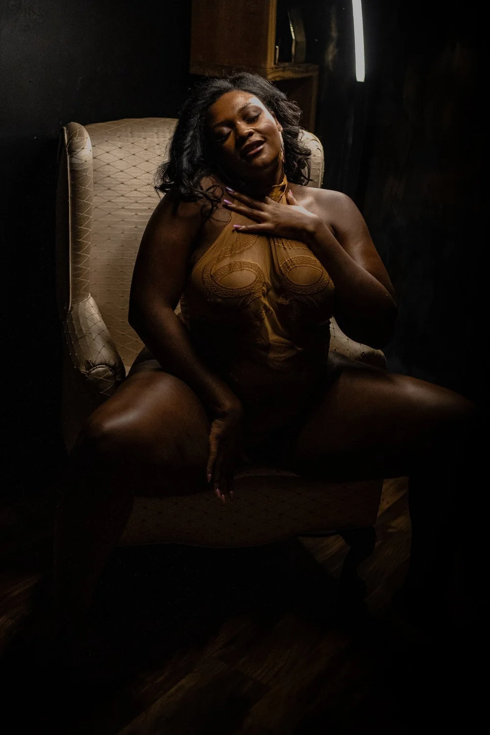 woman in a gold bodysuit seated on a chair during a boudoir photography session at The Boudoir Studio in Jefferson NC
