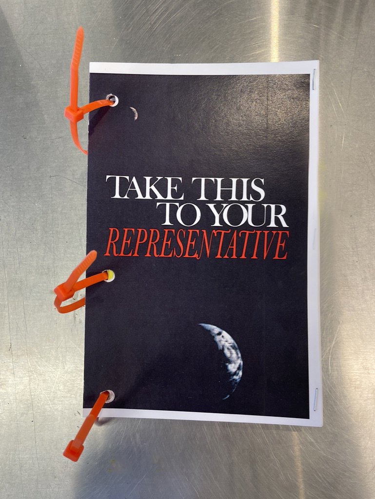 “Take This to Your Representative.” Artist’s Book, front cover. Digital color print, zip tie binding. 25 pages. 8.5 in. 4 in. Course: Book Arts (Printmaking).