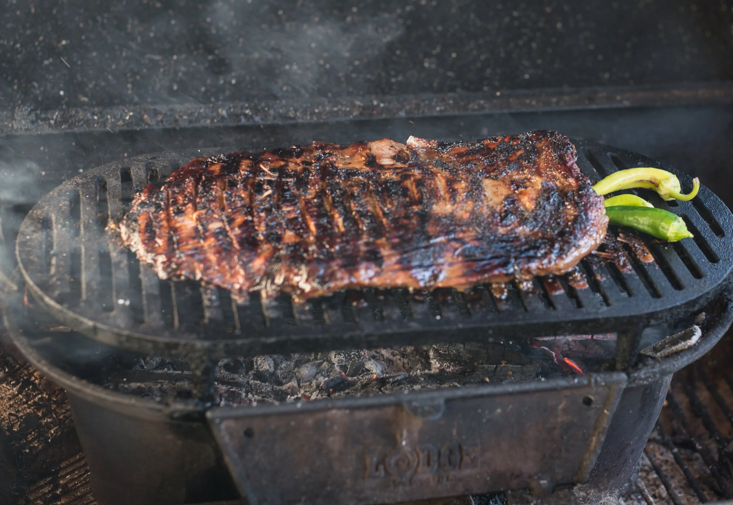 skirt steak over charcoal with chili peppers