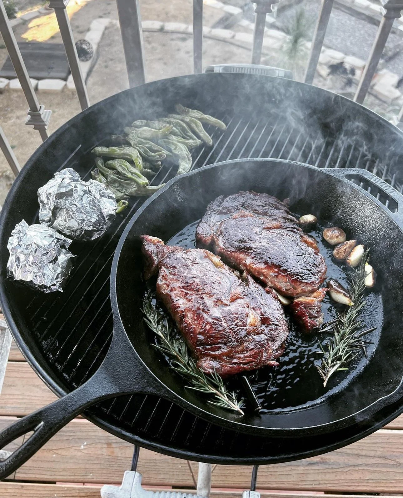 steaks in a cast iron grill on a weber kettle