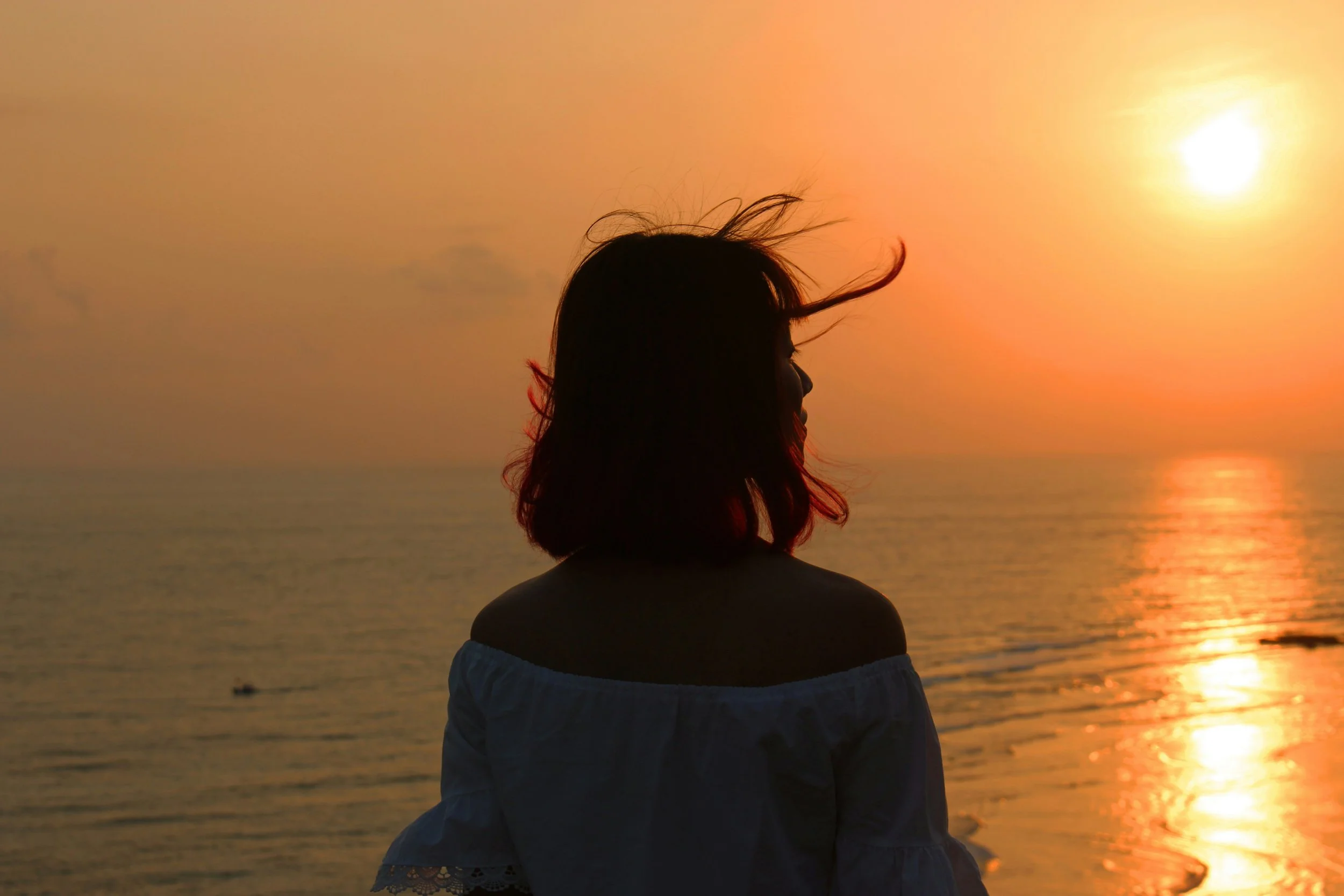 woman in front of the water at sunset