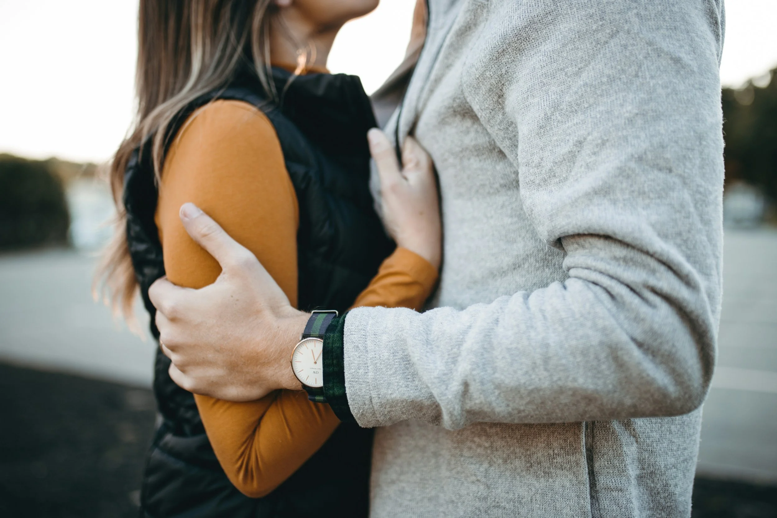 woman in orange shirt and man in gray sweater embracing