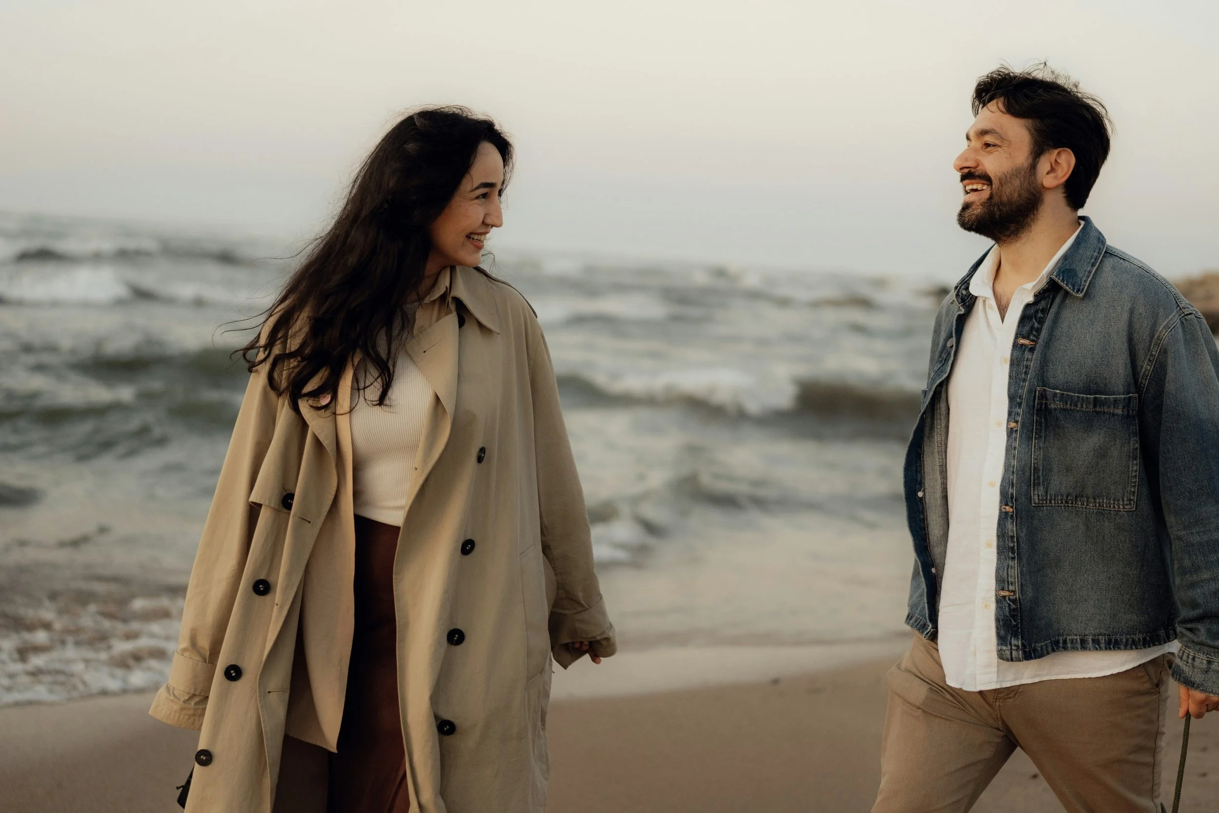 a couple smiles at each other on the beach