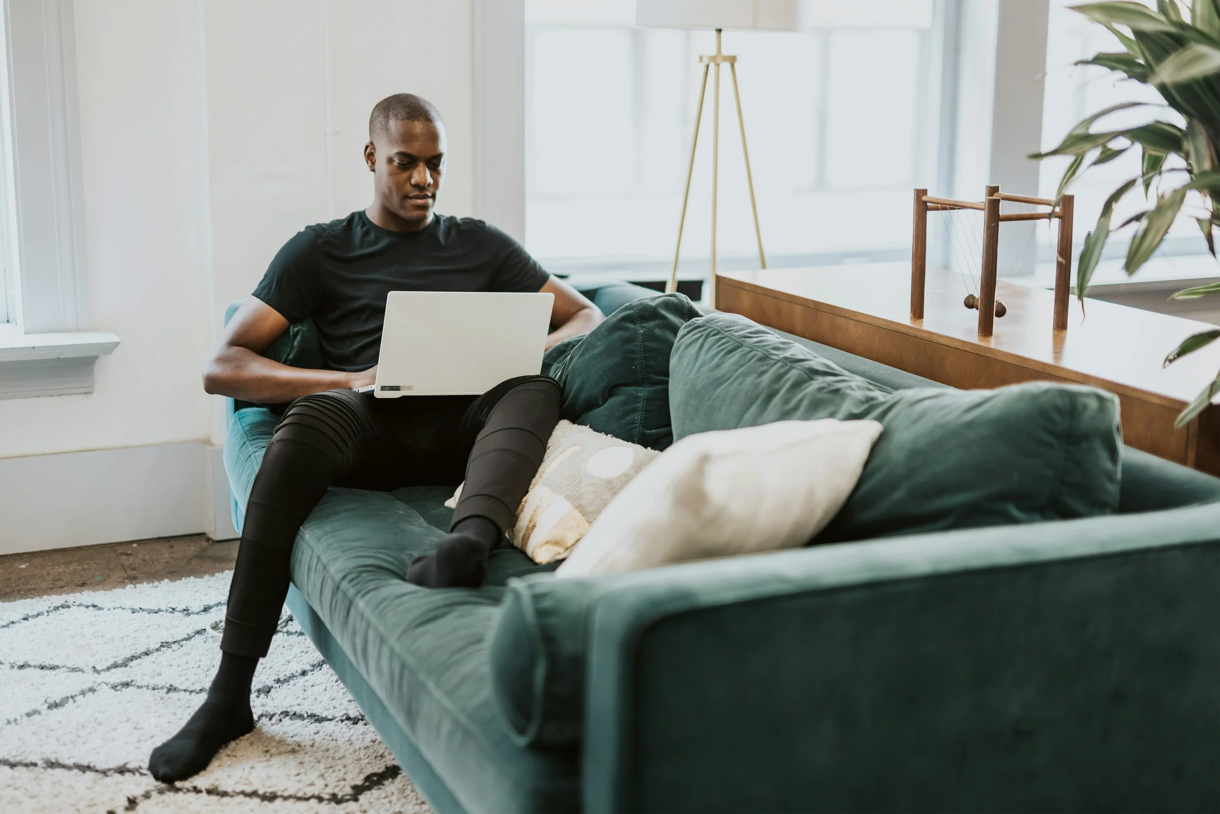 man in black crew neck t shirt and blue denim jeans sitting on green couch
