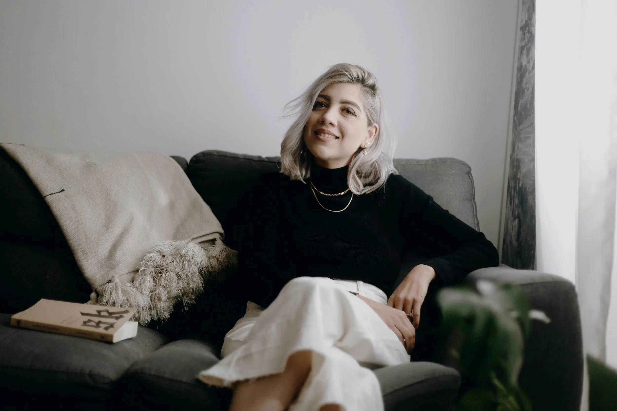 woman in black long sleeved shirt sitting on grey sofa