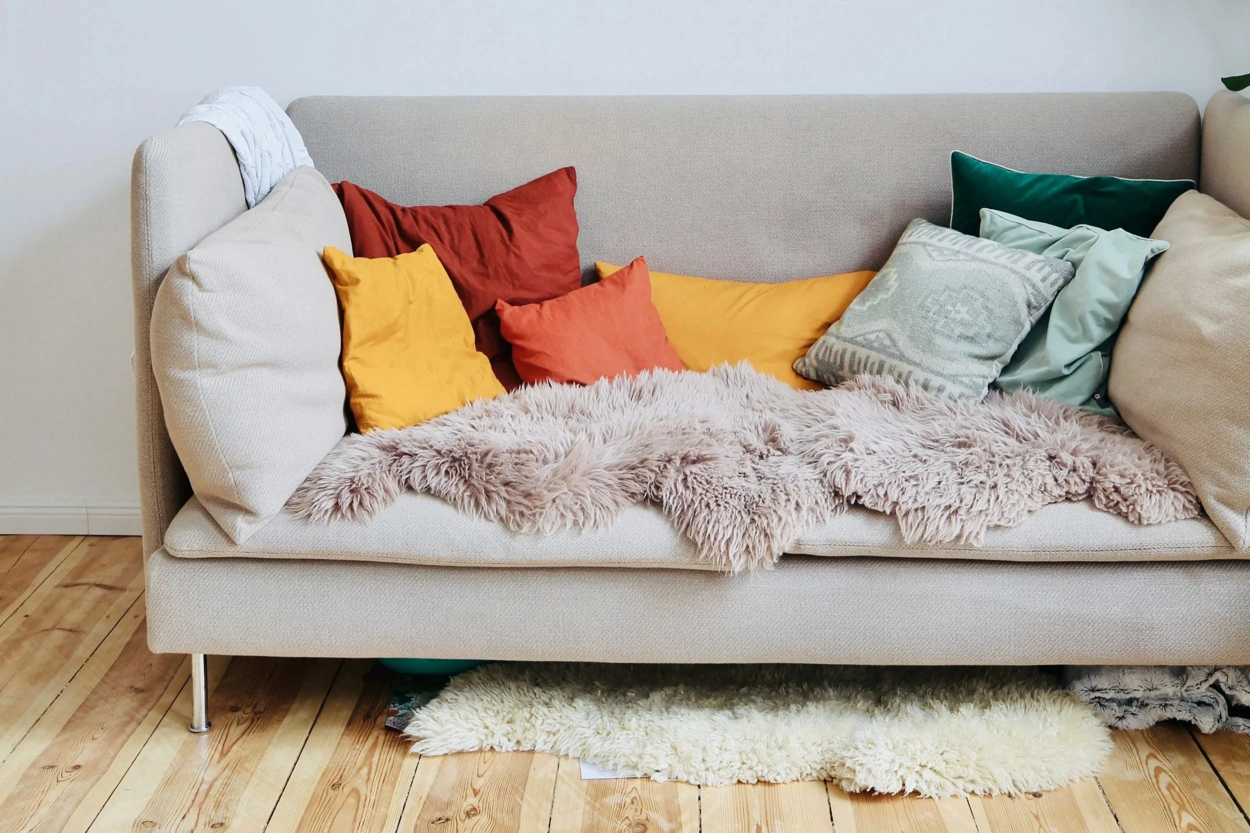 orange yellow and green throw pillows on beige sofa