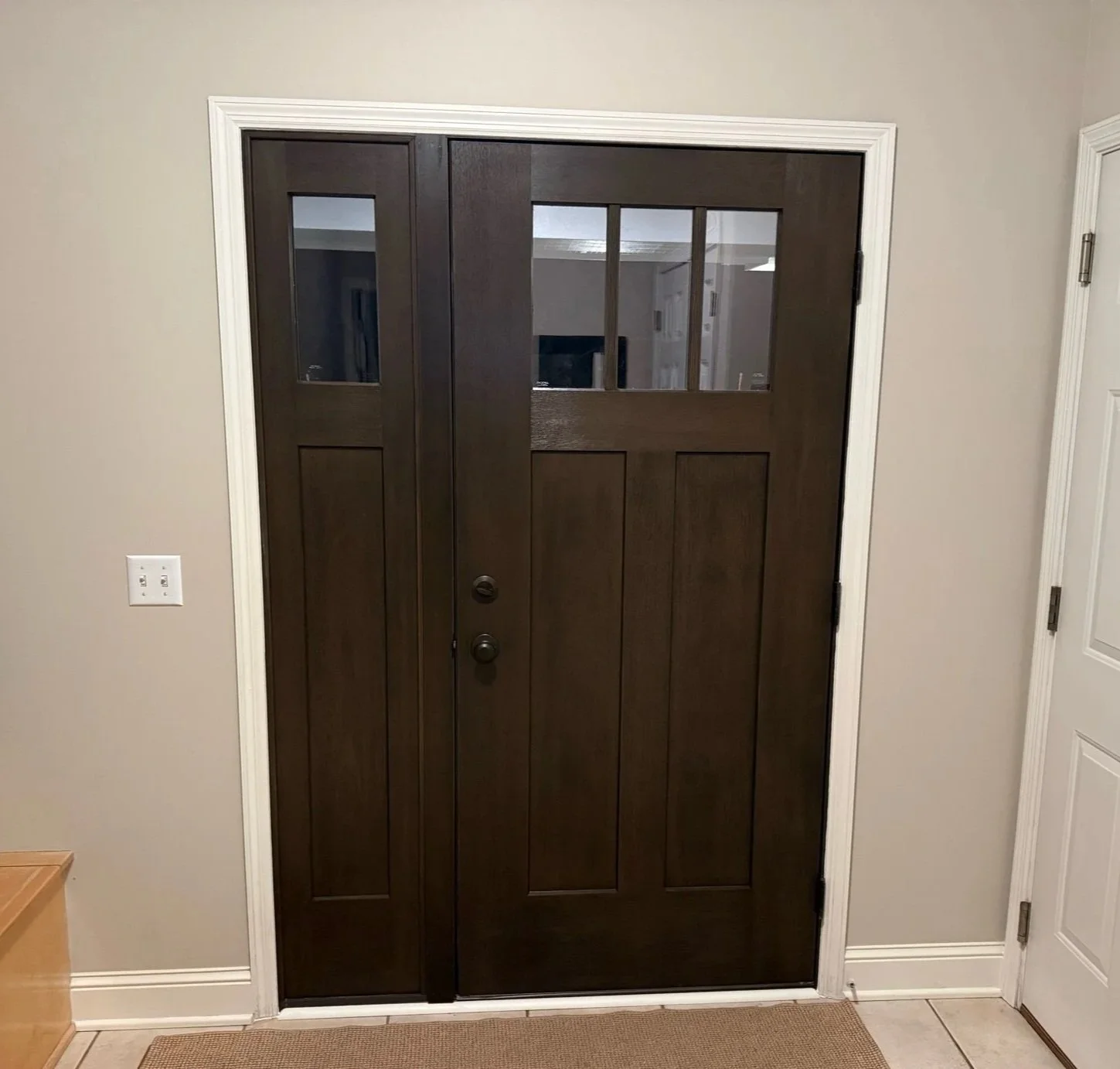 Interior view of side entry door with sidelight in Woodbury, MN showcasing a modern wood door, white trim, and clean foyer design.