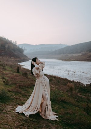 Pregnant woman in white by river on hilside Sacramento pregnancy photographer.jpg