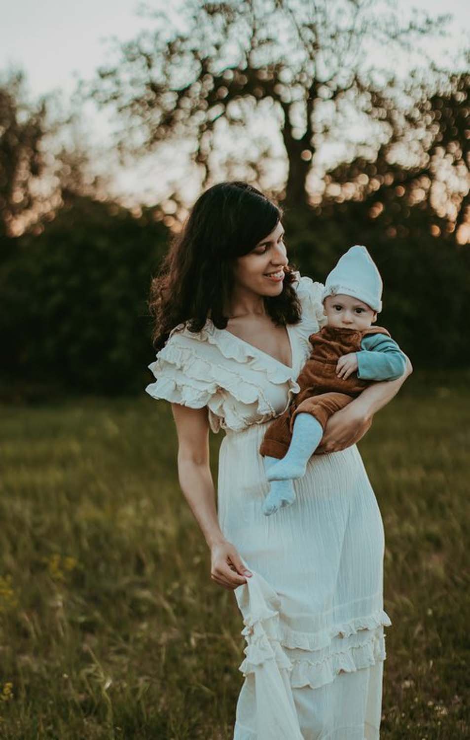 Mother holding baby wearing white at outdoors Sacramento family photos.jpg