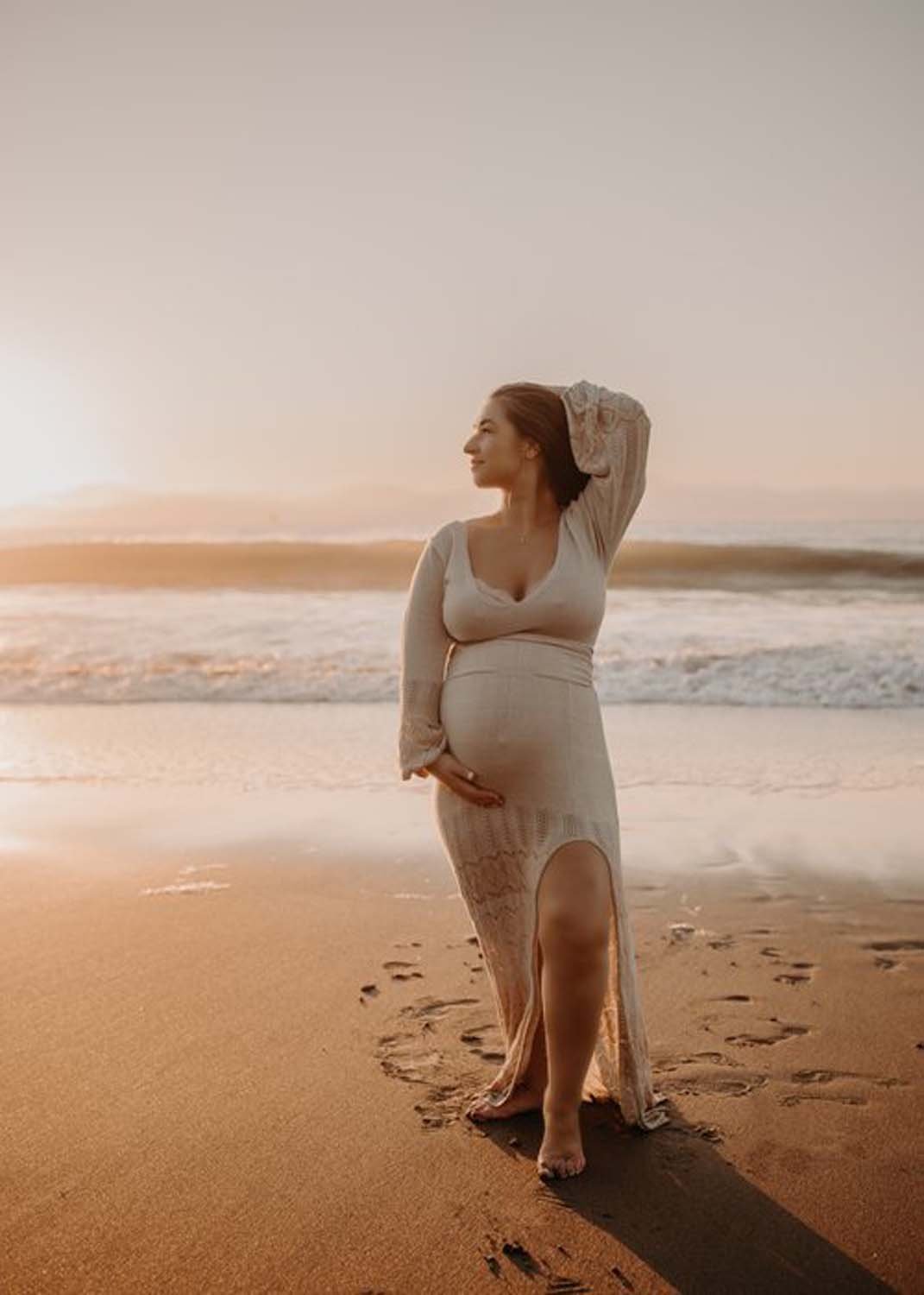 Maternity photo shoot woman holding belly on beach.jpg