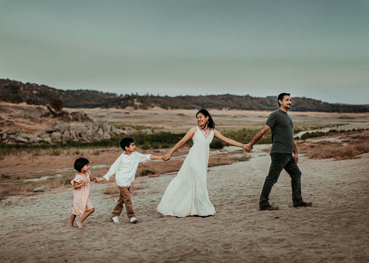 Young family walking outdoors holdong hands in line family portraits.jpg