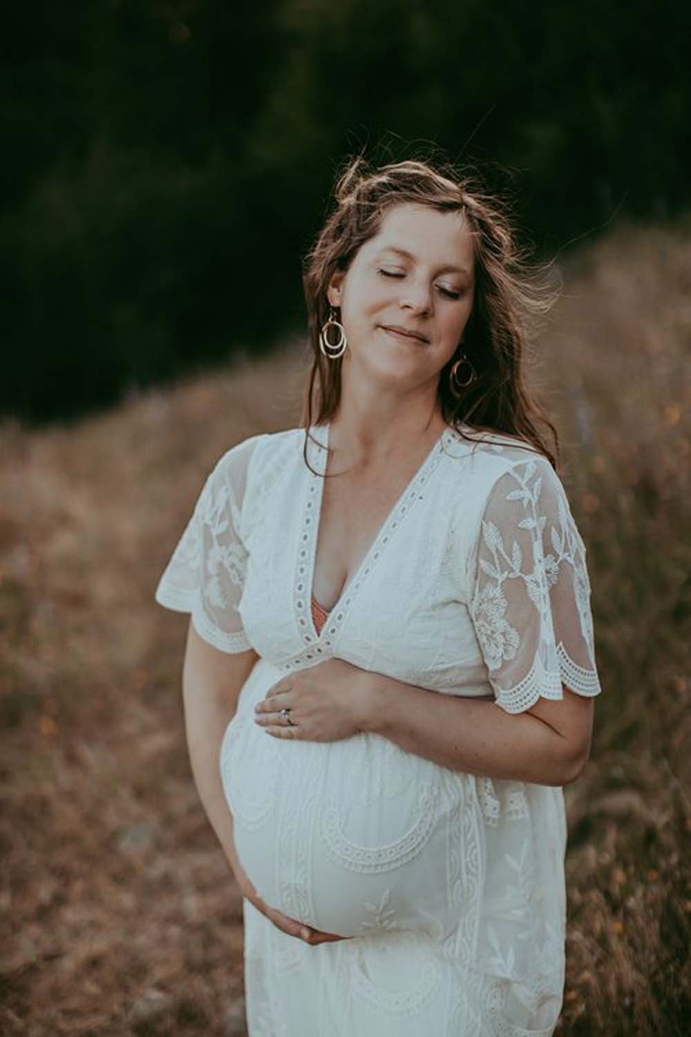 Pregnant woman holding belly in field maternity photos Sacramento.jpg