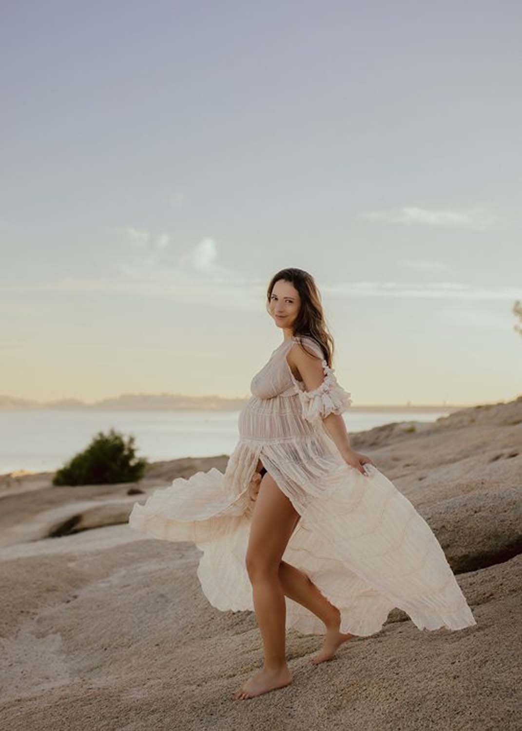 Pregnant woman dressed in white walking on beach maternity photographer.jpg