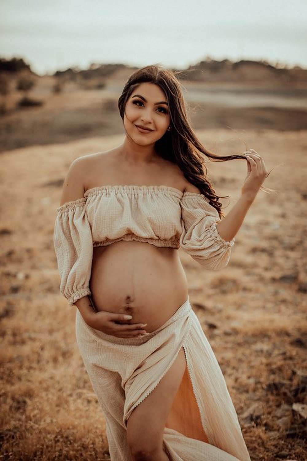 Outdoors in field prenant woman hand on belly maternity photographer.jpg