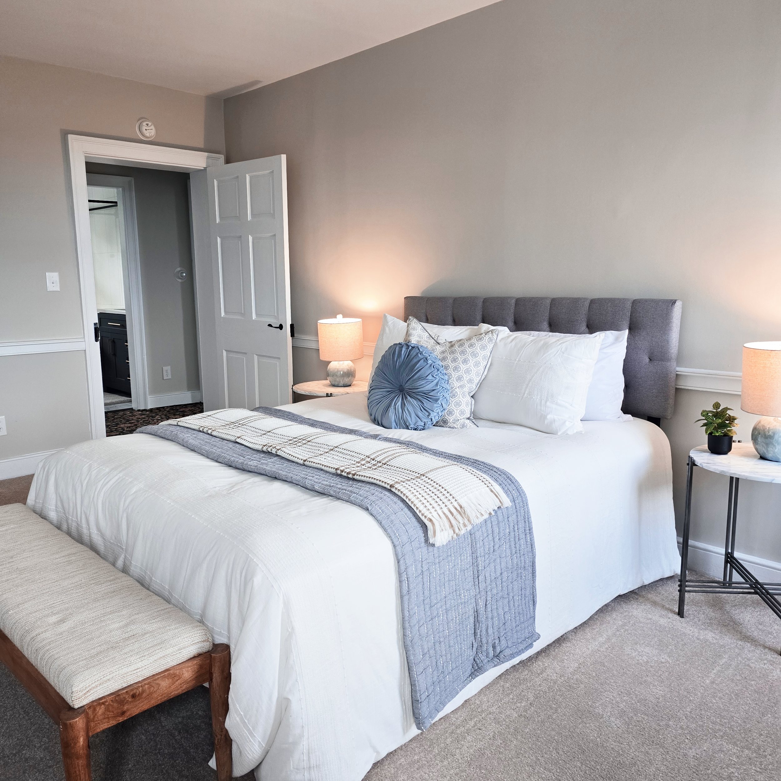 Professionally staged primary bedroom in a Columbia, PA Colonial Farmhouse featuring layered white bedding, soft accent pillows, and neutral décor.