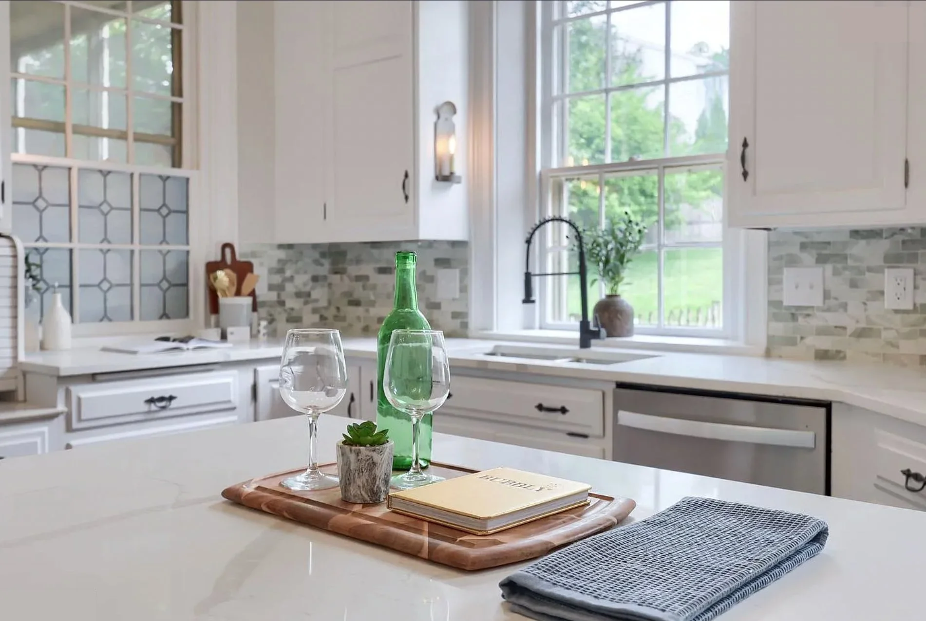 Close-up of a styled kitchen island featuring wine glasses, a decorative table runner, and a wooden cutting board in a professionally staged Columbia, PA home.