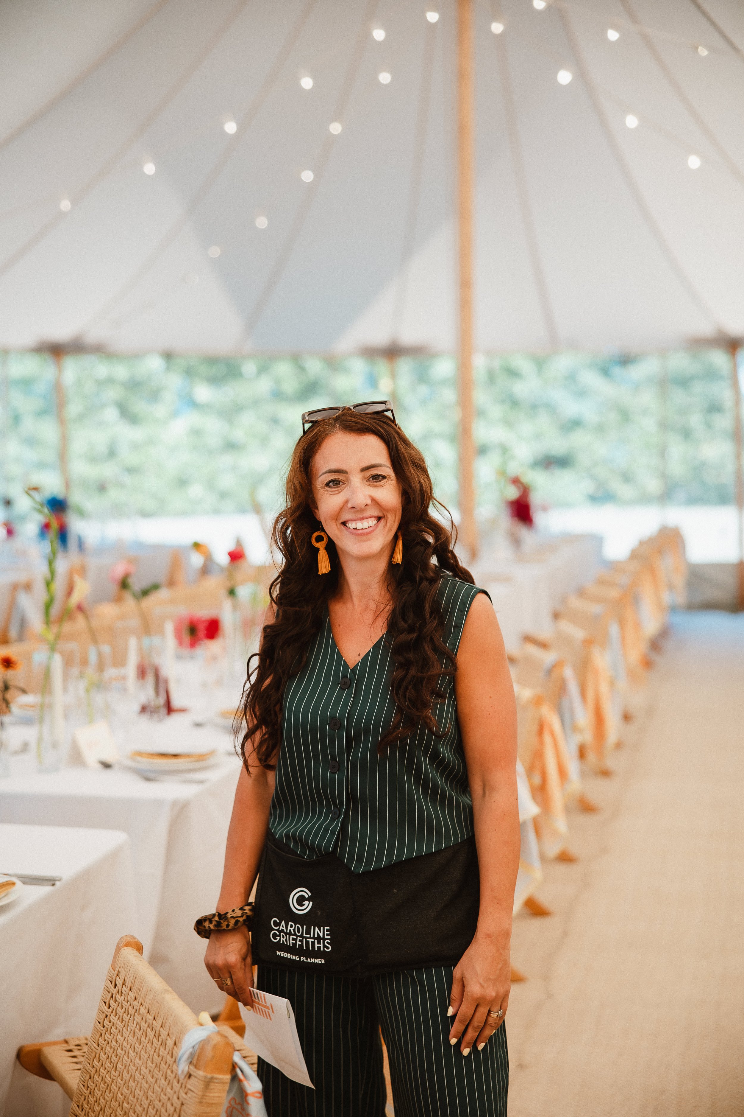 Women standing in a marquee wearing a green pin striped suit at a wedding