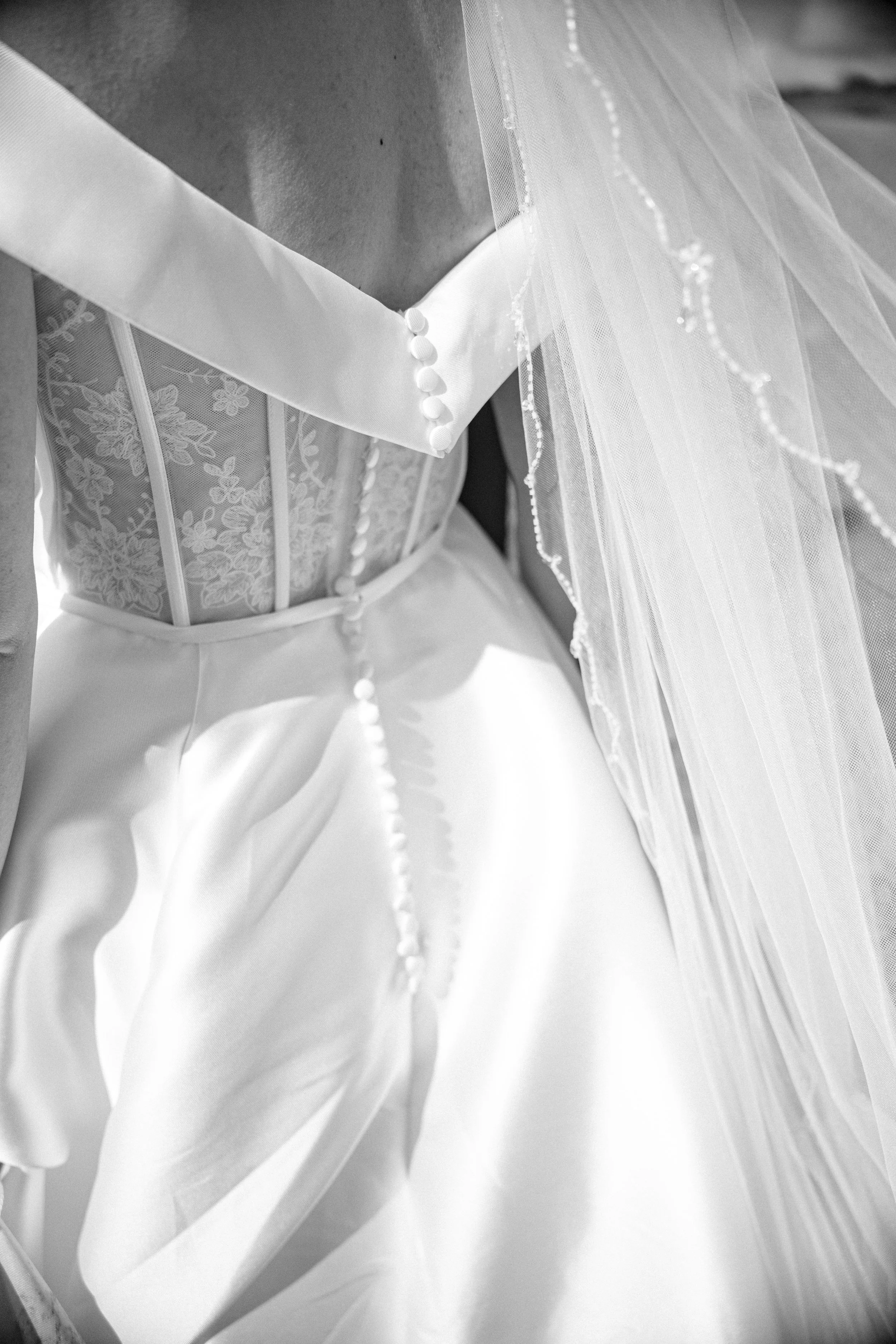 A bride is pictured in a beautiful garden wearing a full sleeve Ladybird wedding dress, holding a bouquet