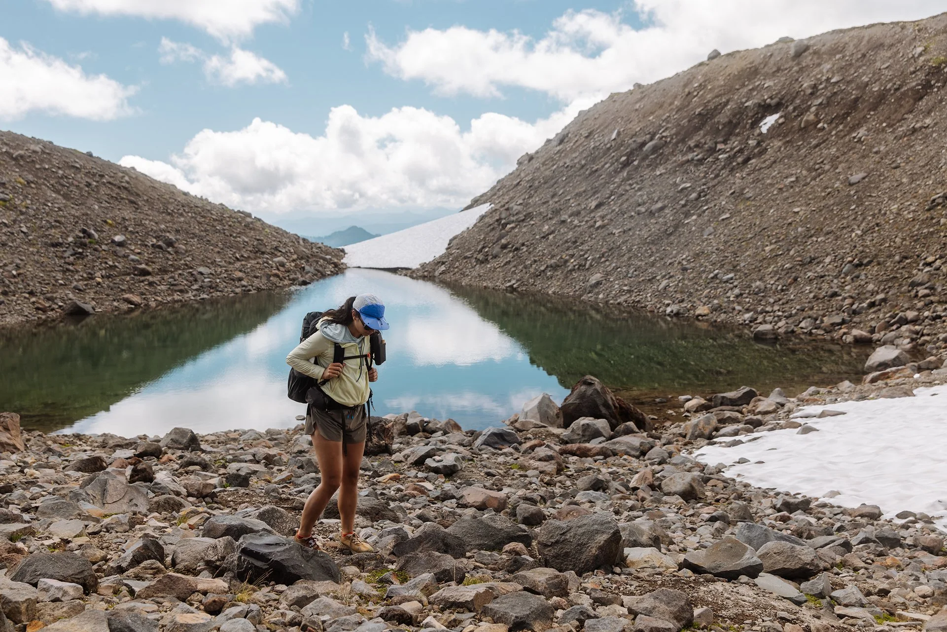 Parapack P-CAP LITE Ultramarine on woman hiking near an alpine lake, 5-panel sport cap, ultra lightweight, breathable mesh, compact, moisture wicking, unisex, UPF 50 headwear for travel, hiking, urban outdoors, photo by Jamie Cooper
