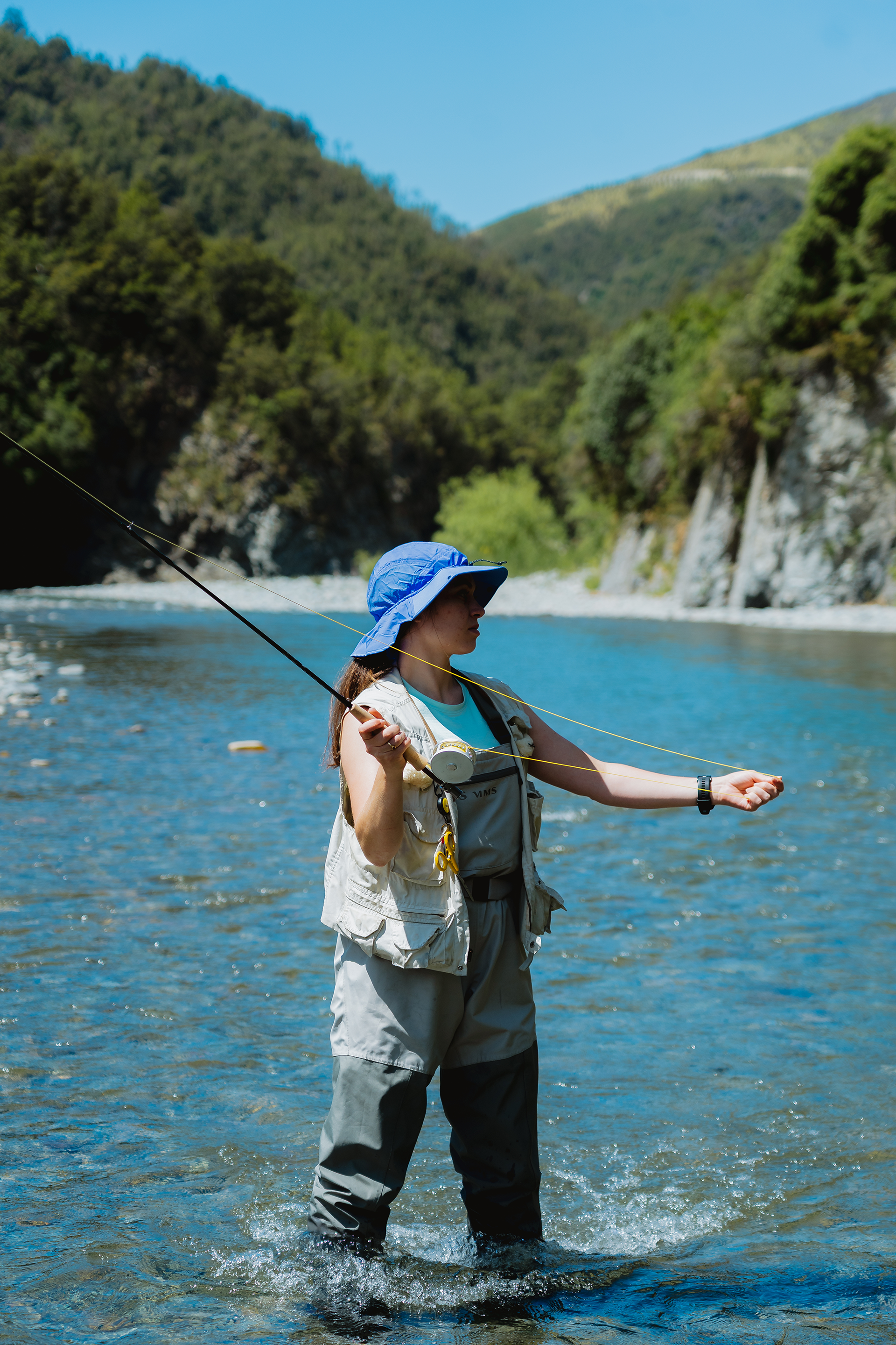 Person fly fishing in a river surrounded by summer landscape in Australia