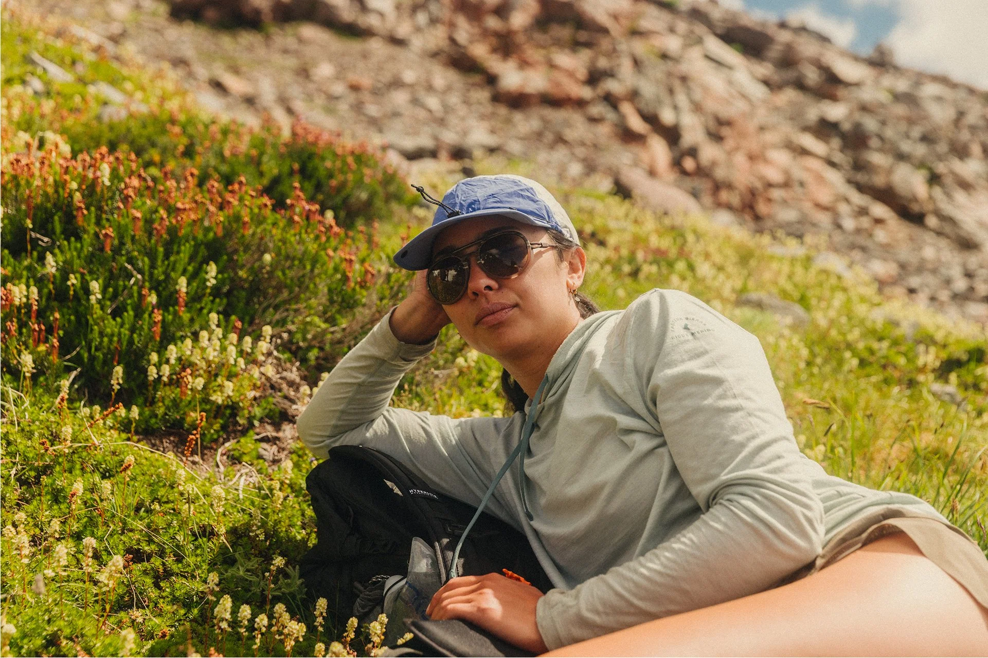 Parapack P-CAP LITE Ultramarine on woman resting in some foliage, 5-panel sport cap, ultra lightweight, breathable mesh, compact, moisture wicking, unisex, UPF 50 headwear for travel, hiking, urban outdoors, photo by Jamie Cooper