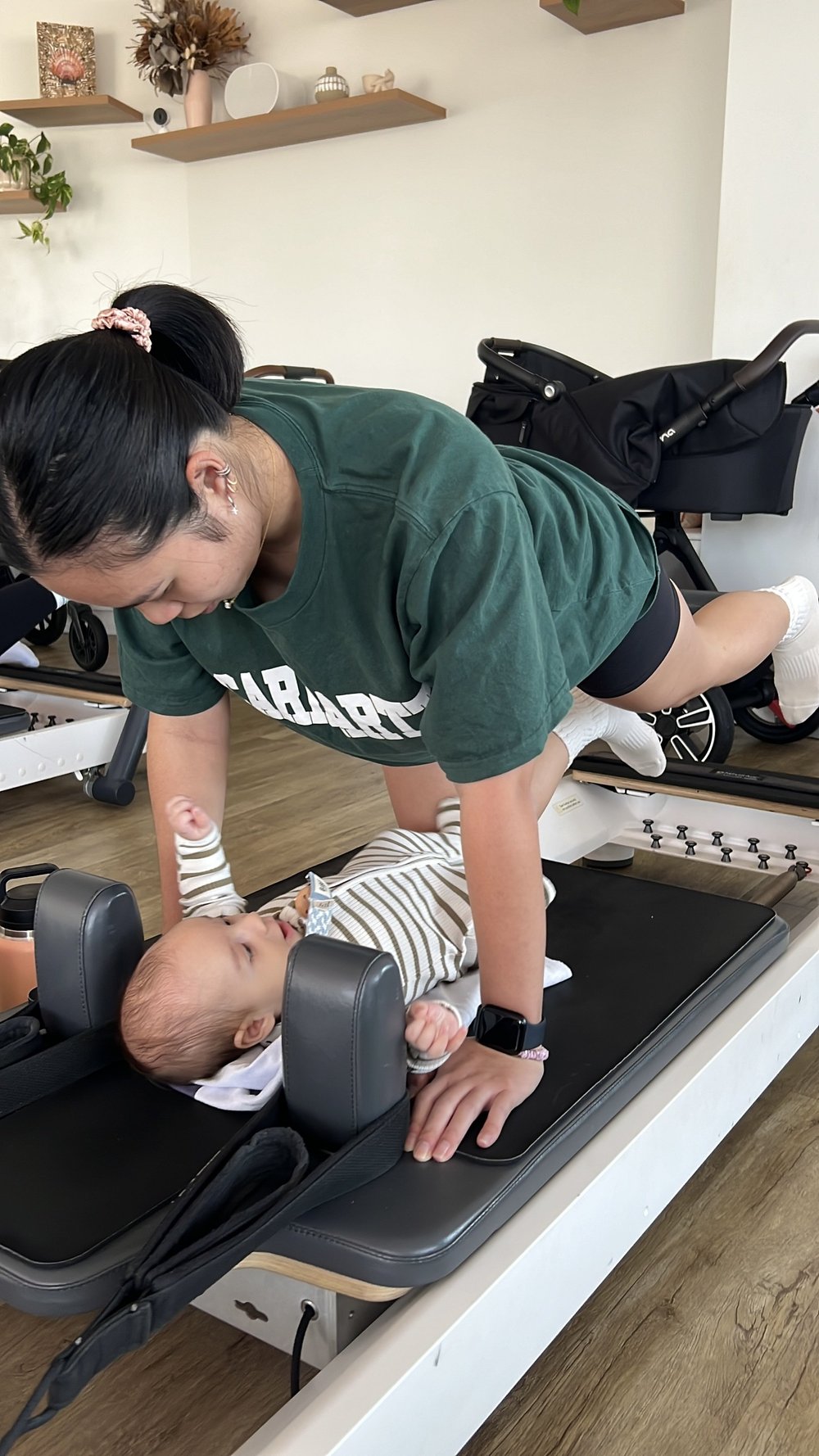 A mum training on the reformer with her baby beside her