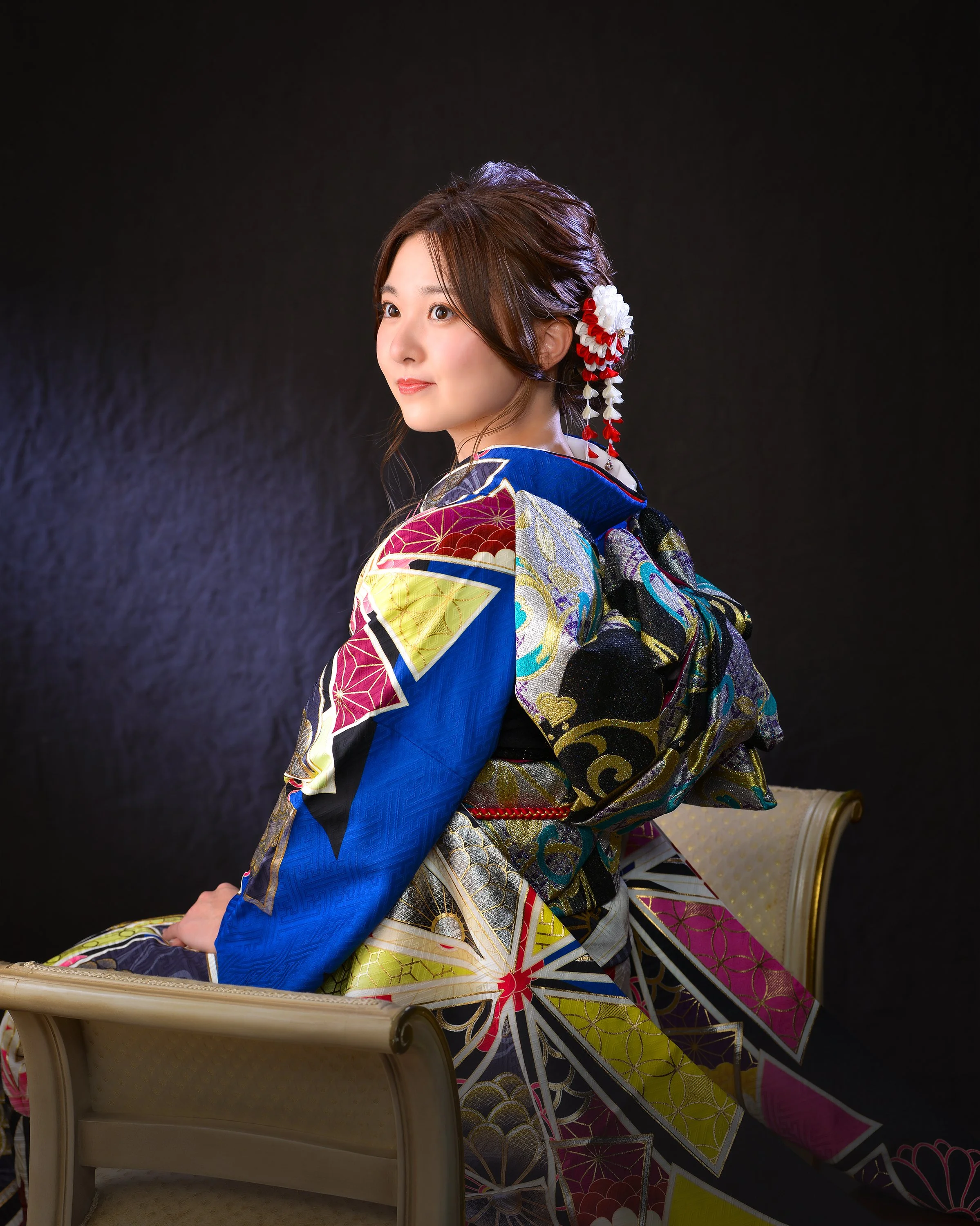 色とりどりの着物を着た若い女性が椅子に腰掛けている写真