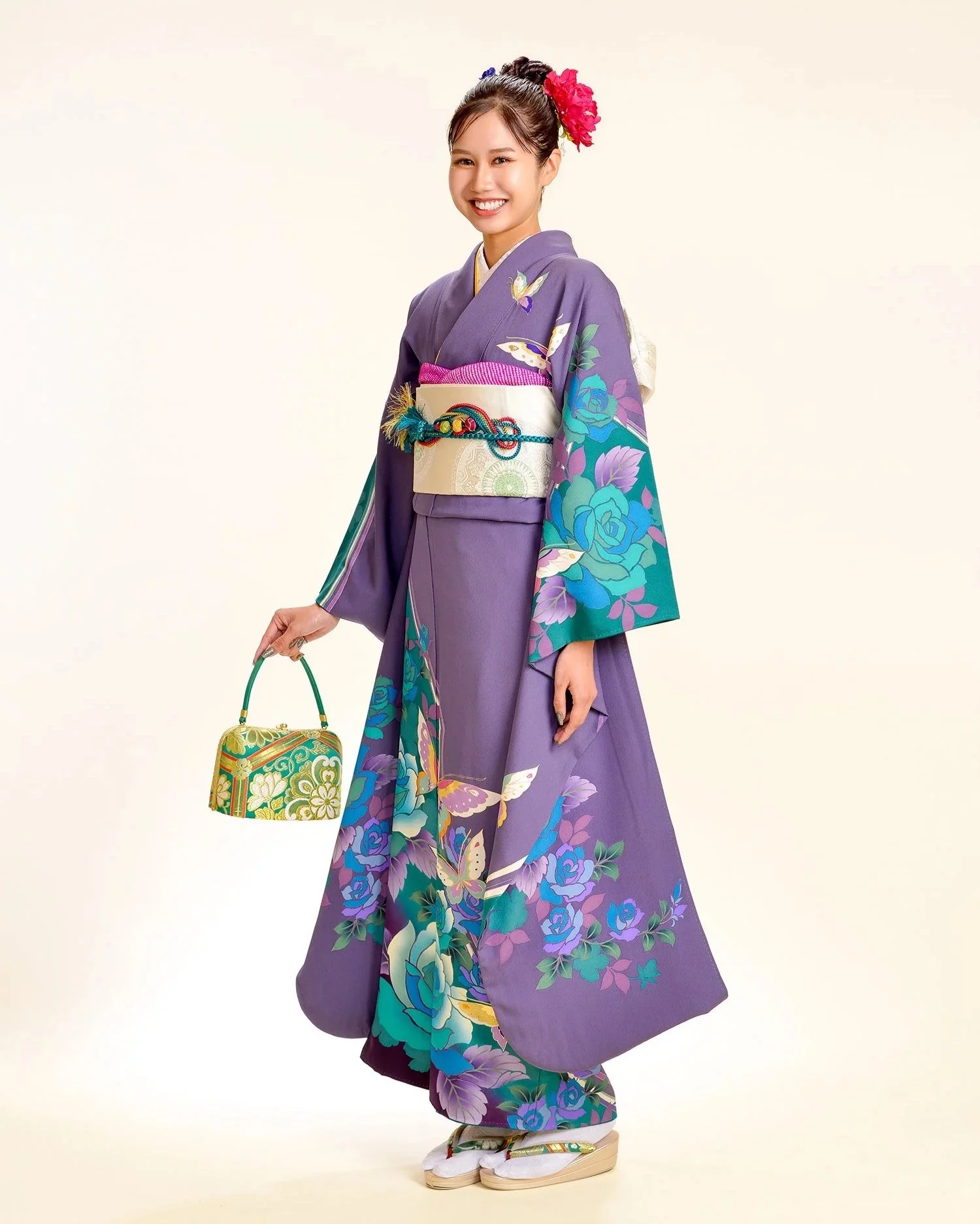 紫色の着物に花と蝶の模様を着た女性が笑顔でポーズを取っている