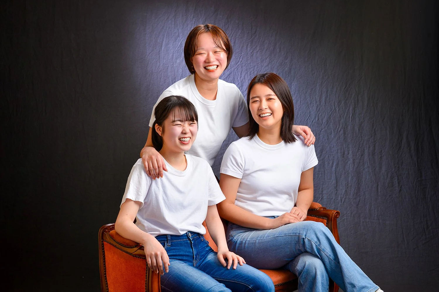 笑顔の三人の女性が黒い背景の前でポーズを取っています。