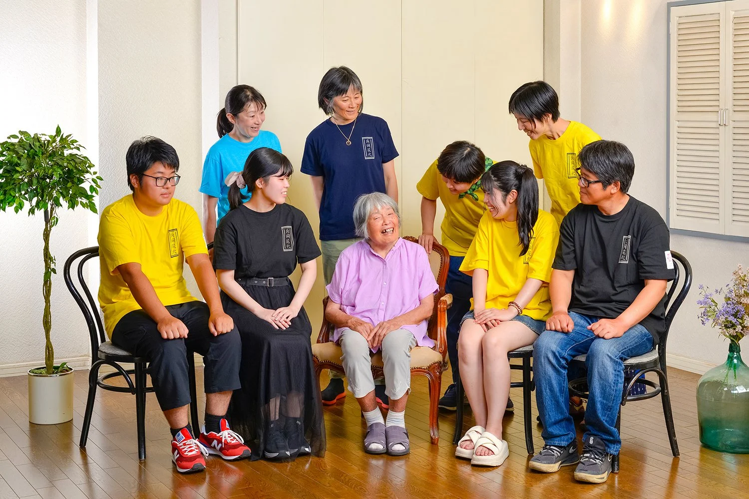 老人と若い人々が笑顔で交流しているグループ写真