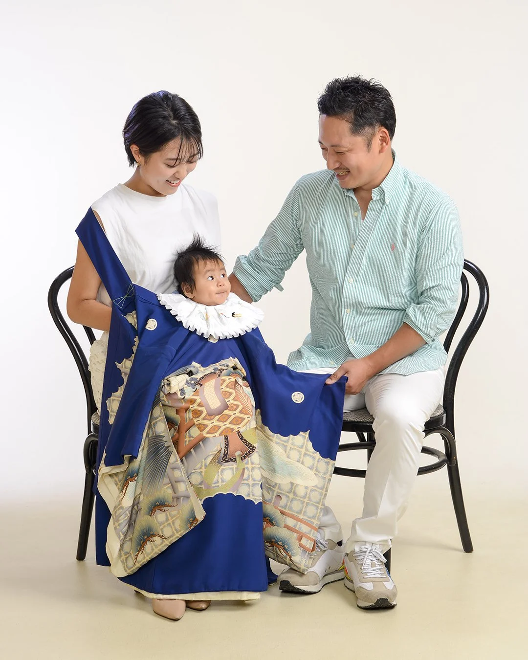 家族が赤ちゃんのお宮参りの衣装を見せている写真
