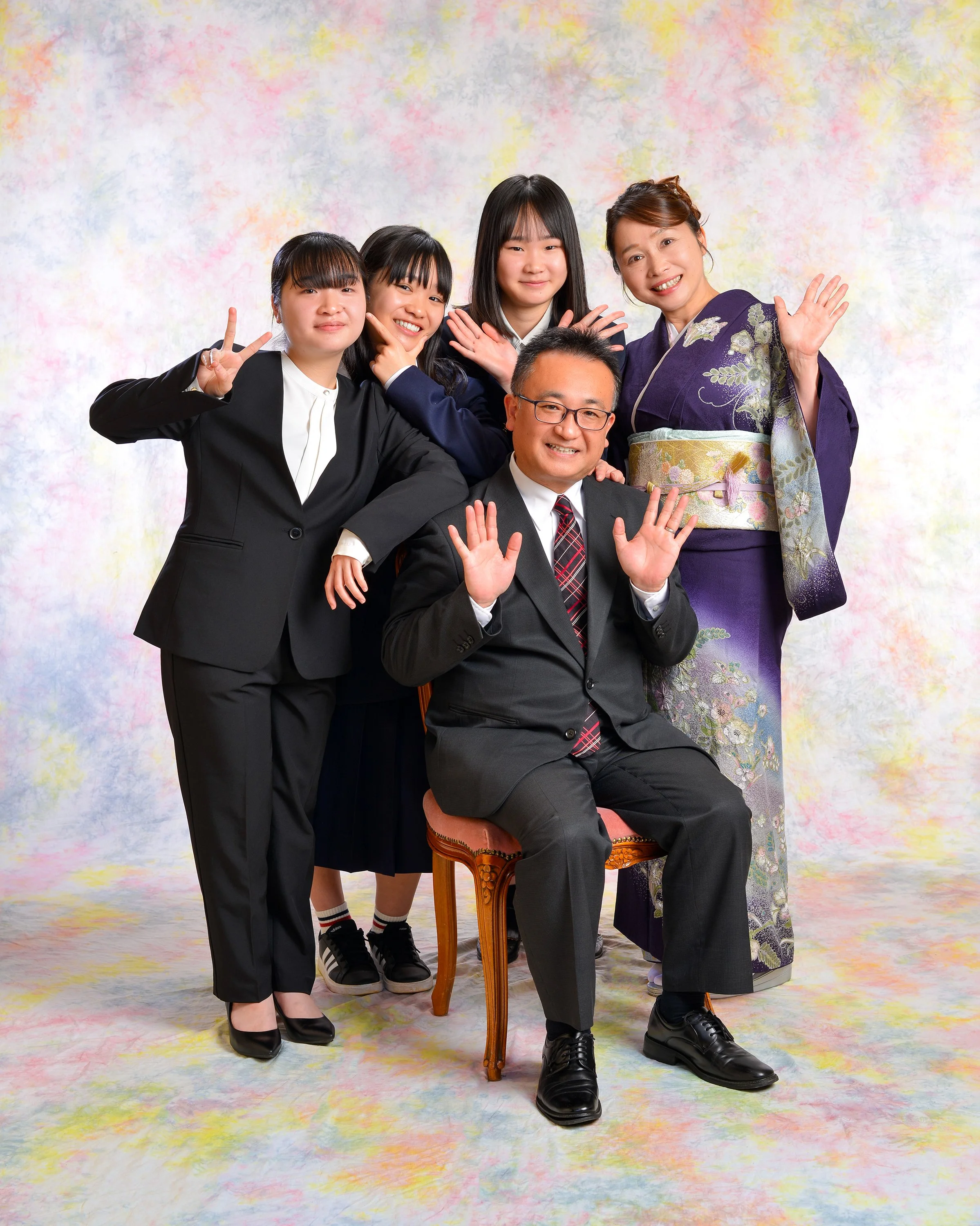 男性と女性五人がカラフルな背景の前でポーズをしている集合写真。