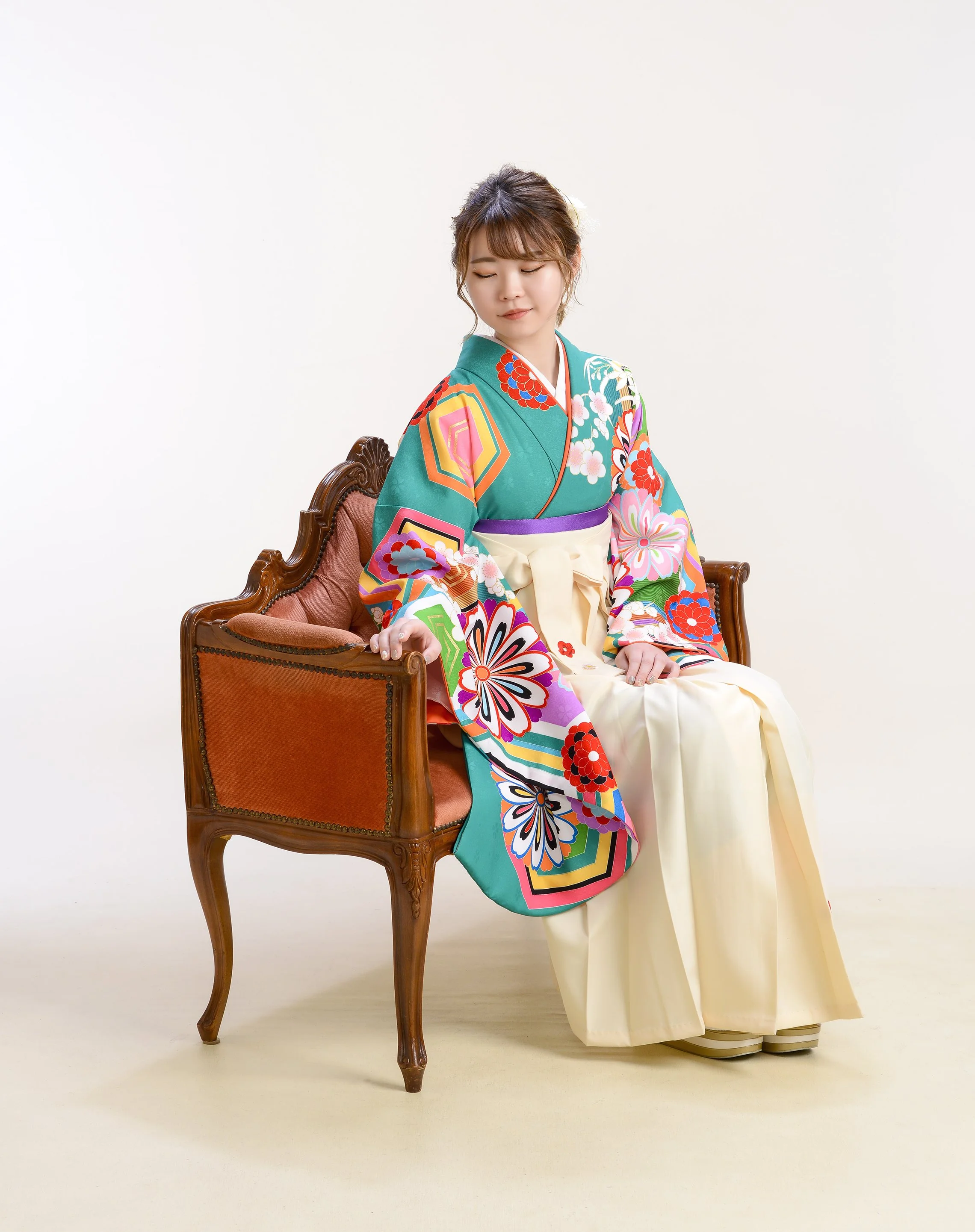 色とりどりの着物を着た女性が椅子に座っている。白い背景。」}】%{
