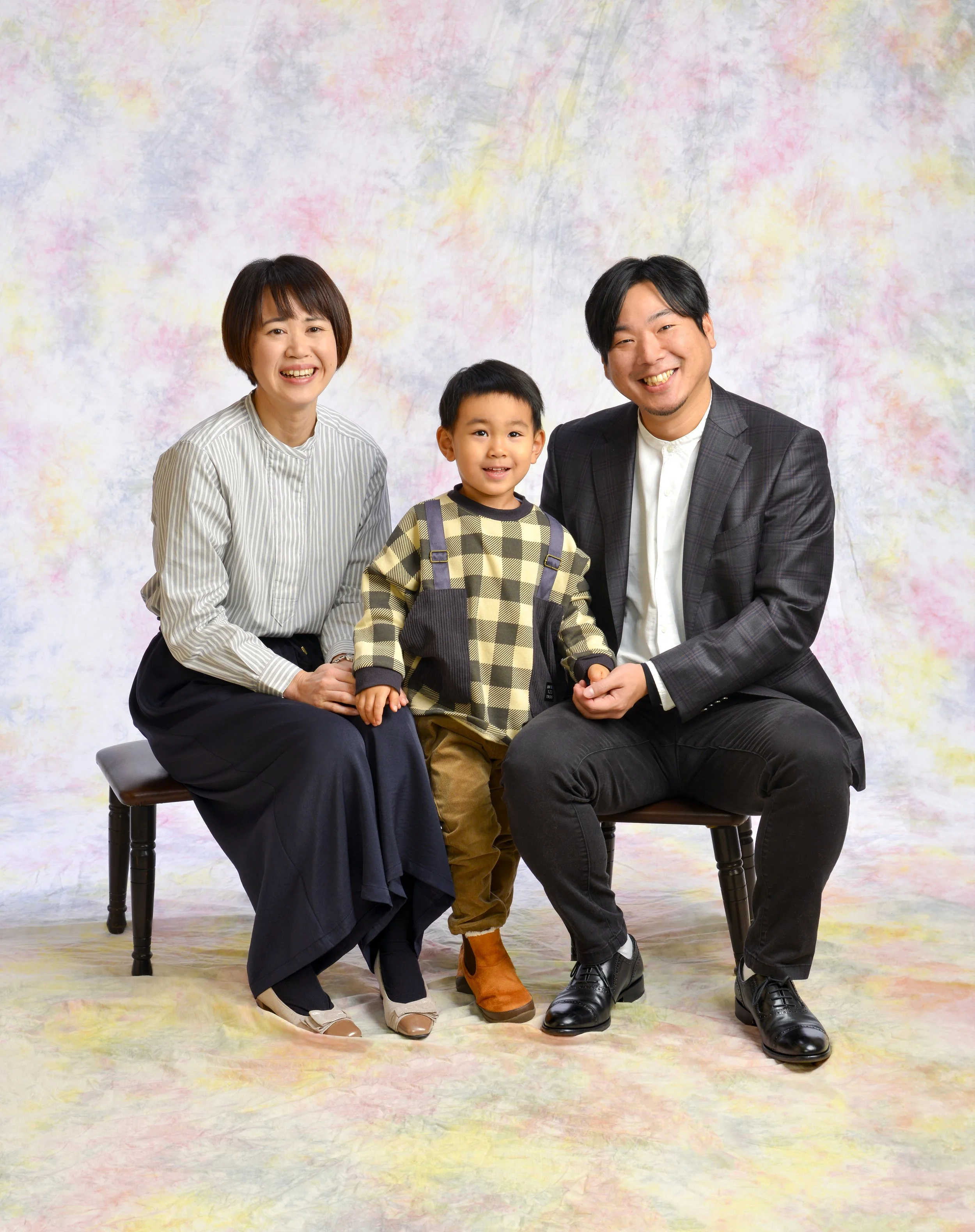 家族写真、男女二人と一人の子供が笑顔でポーズ。