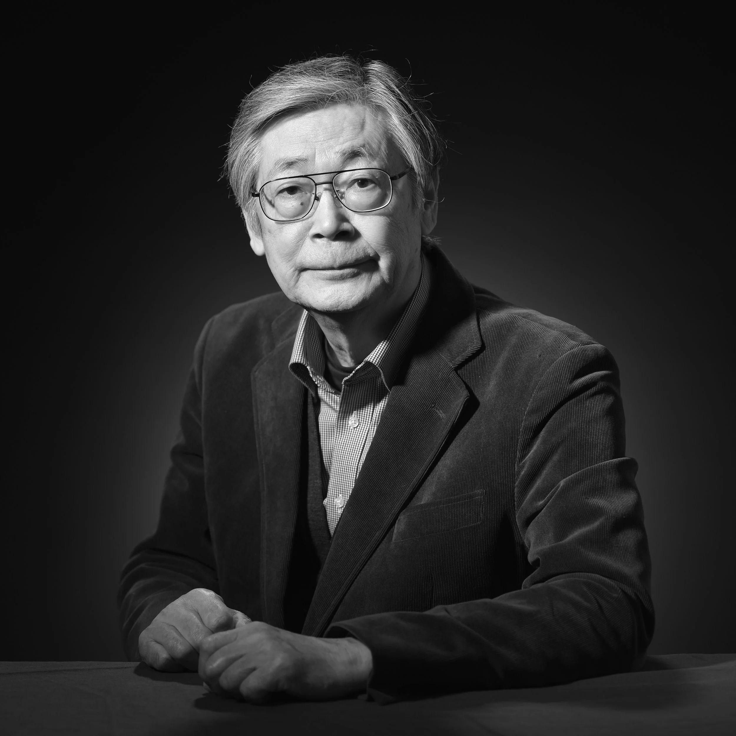 グレーのスーツを着て、眼鏡をかけた中年の男性の肖像写真