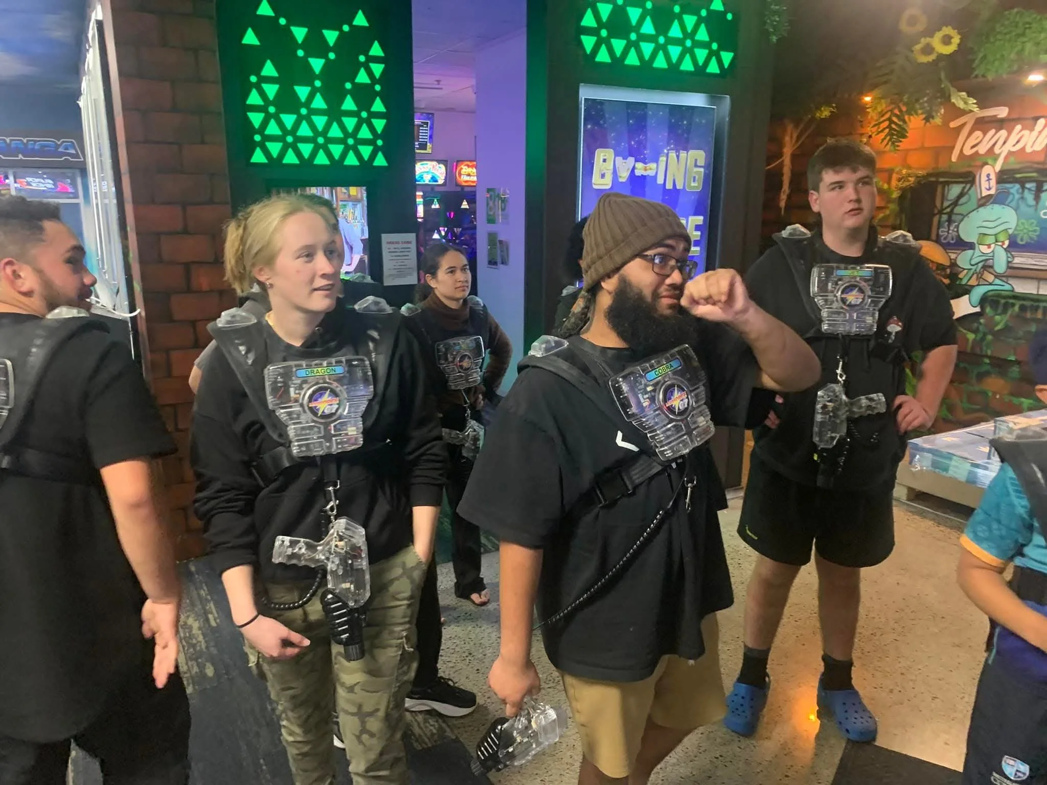 Group of people wearing laser tag vests in an indoor arcade or entertainment center
