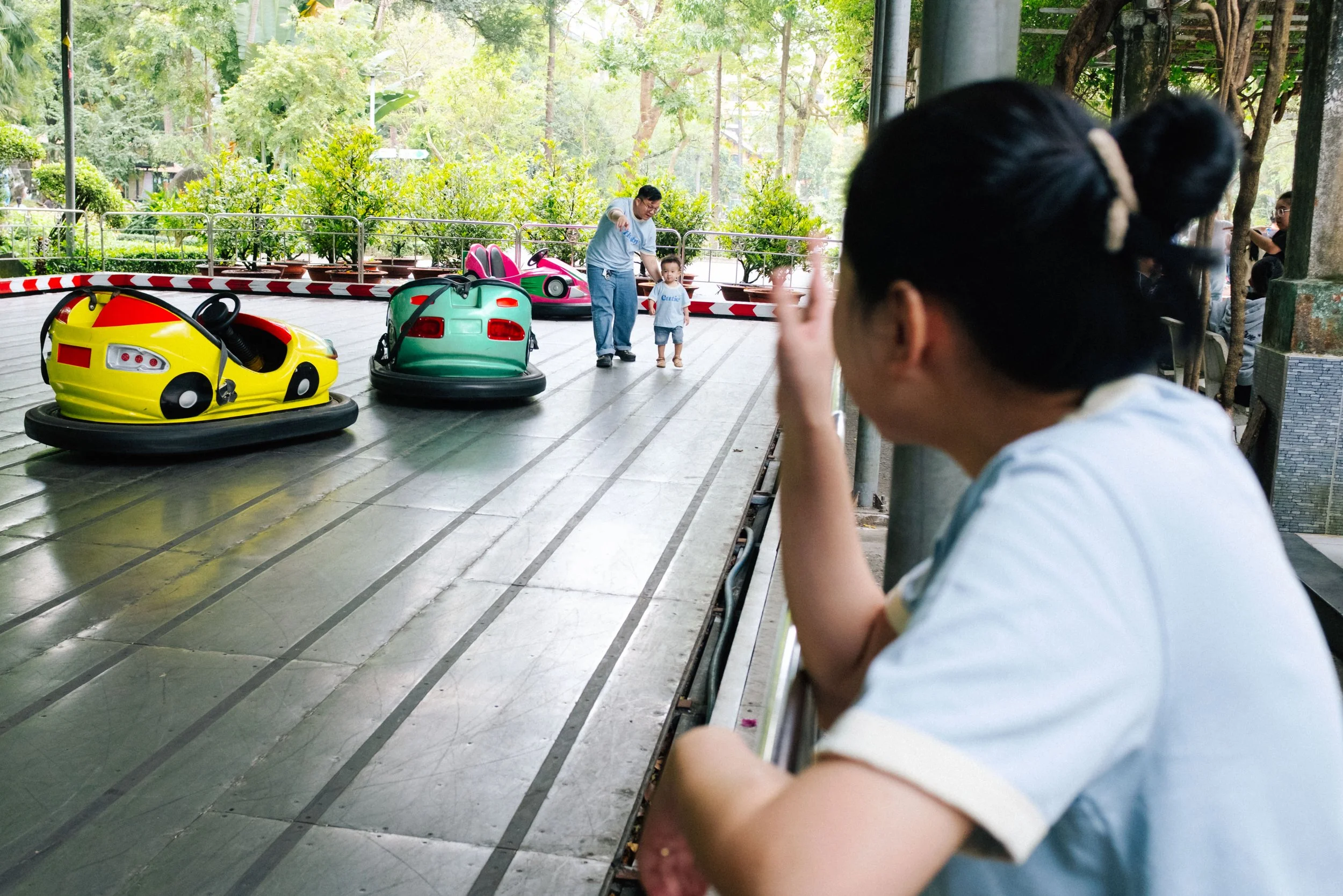 A woman watching children ride bumper cars at an amusement park during daytime.