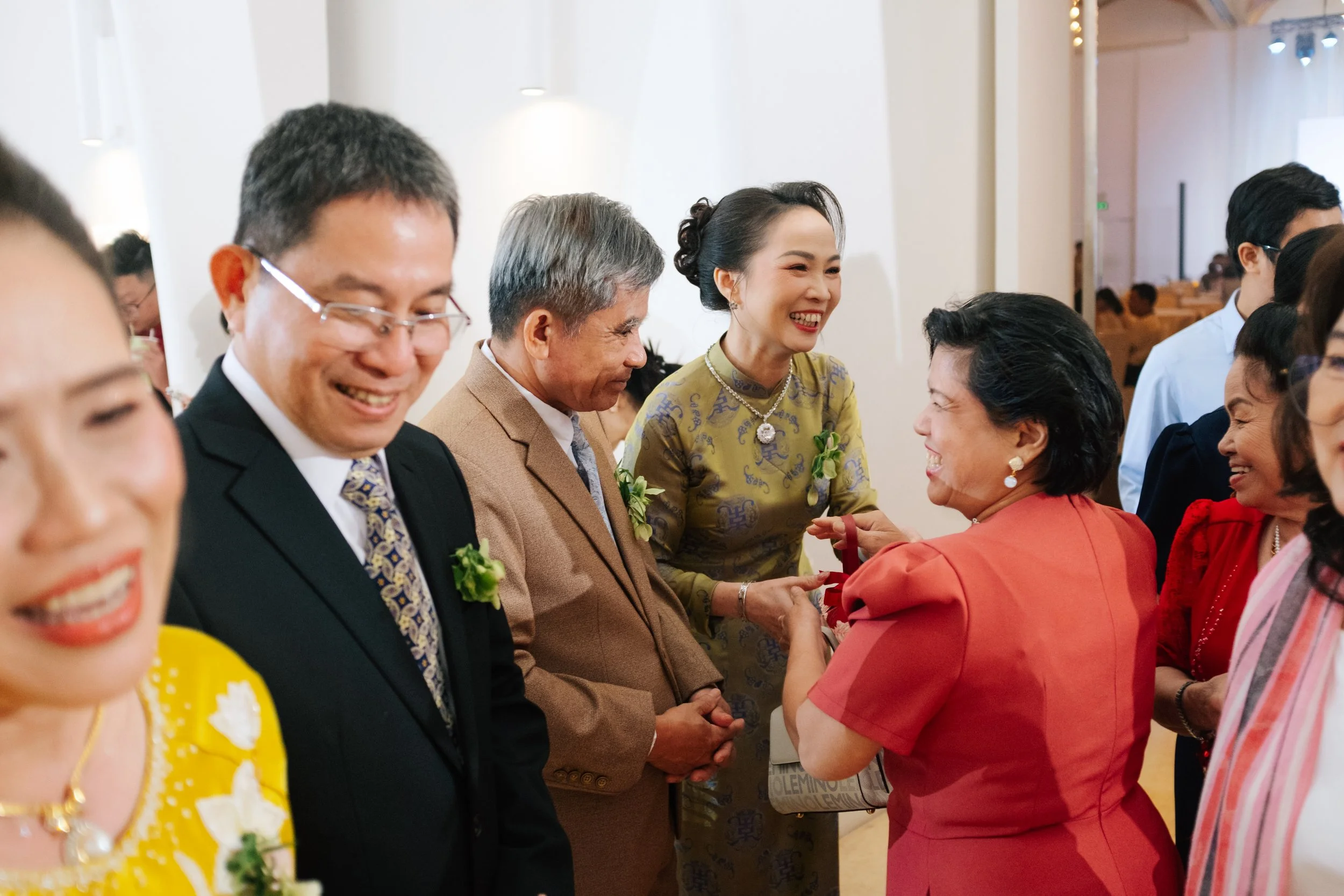 People at a social gathering chatting and smiling, some wearing formal and colorful attire.