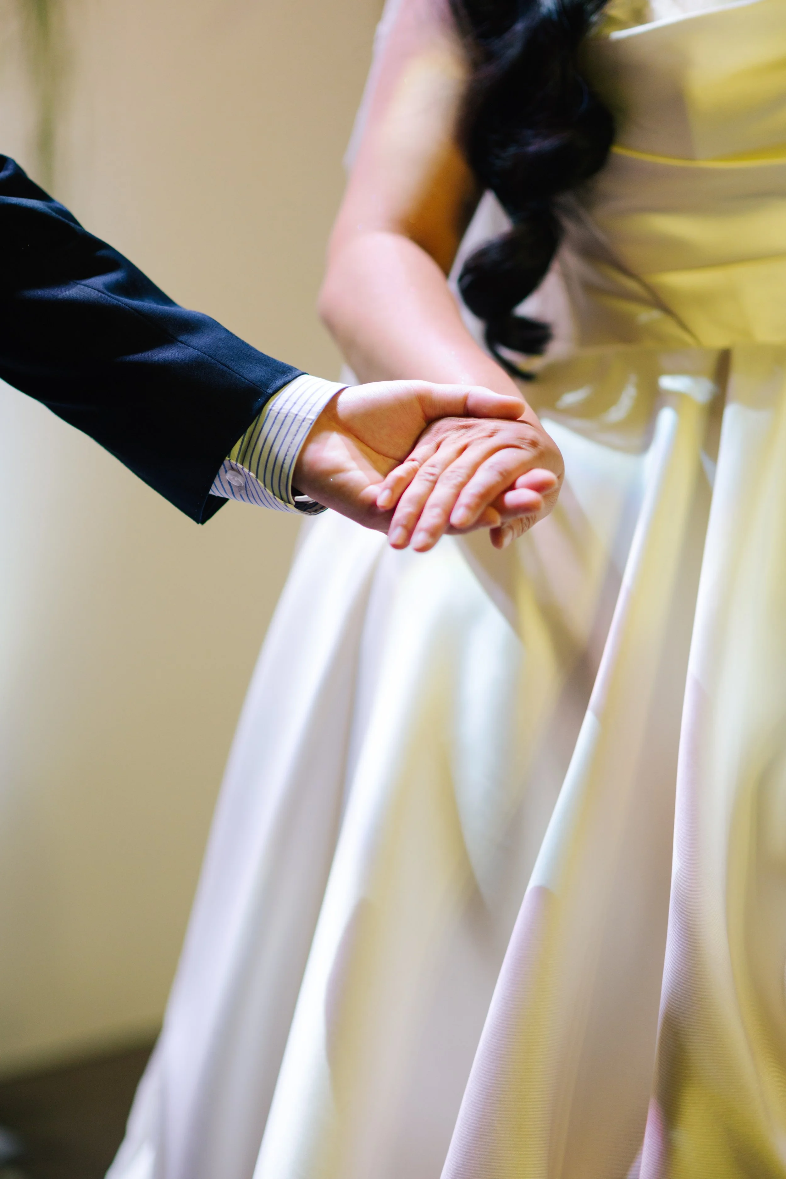 A bride and groom holding hands during their wedding ceremony.