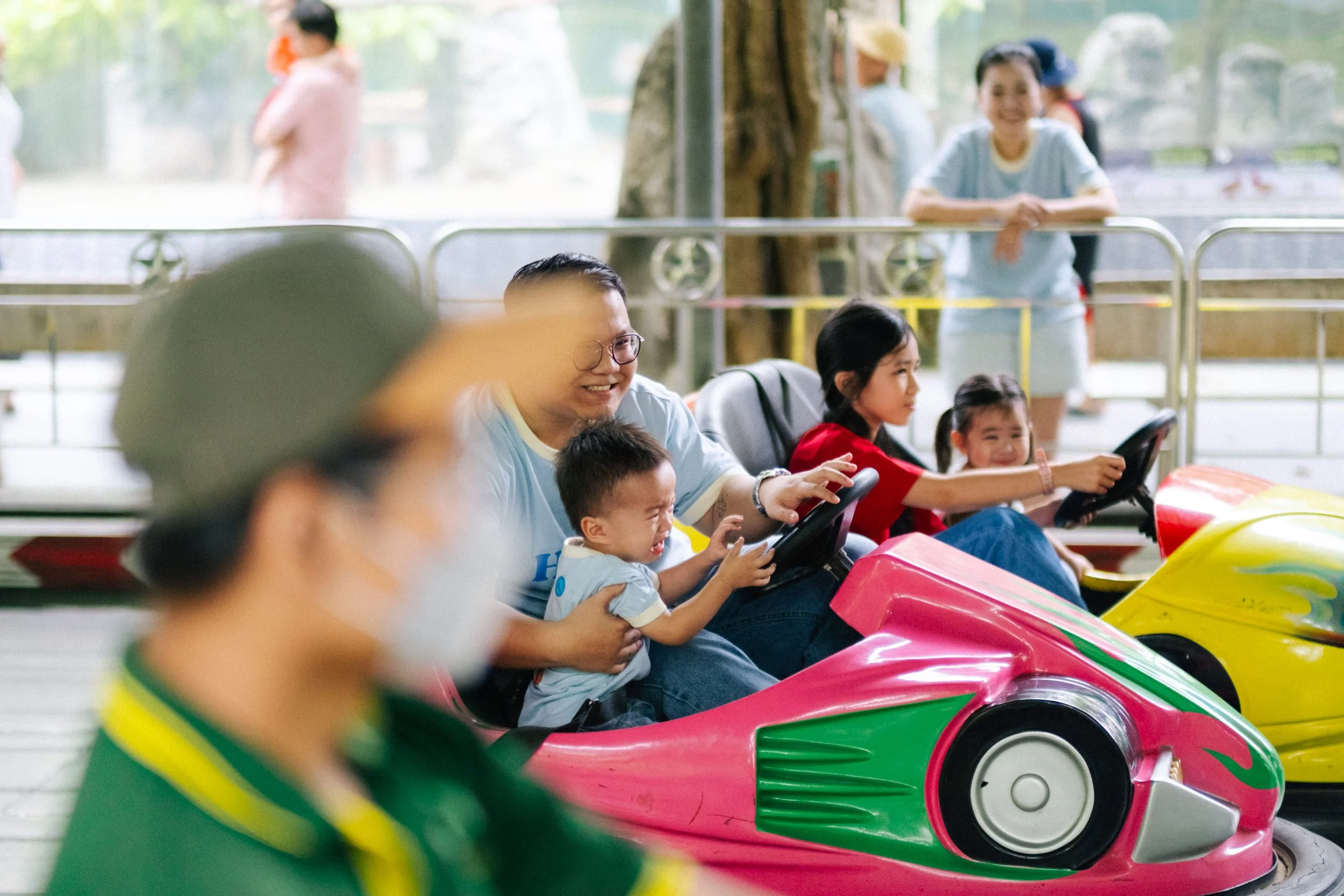 People enjoying a ride on a colorful bumper car attraction at an amusement park or arcade.