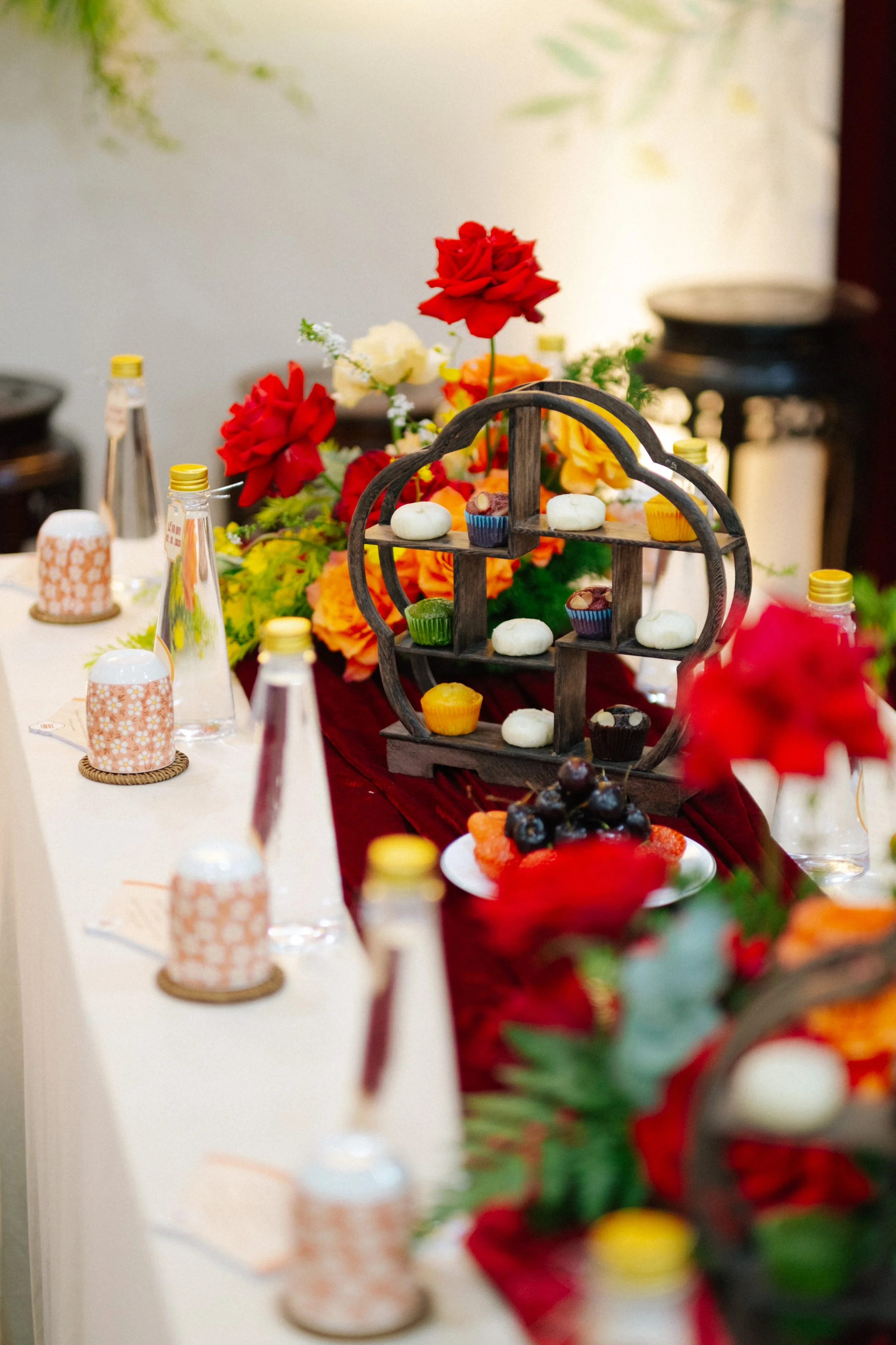 Decorative table setting with colorful flowers, cupcakes, and chocolates artfully arranged.