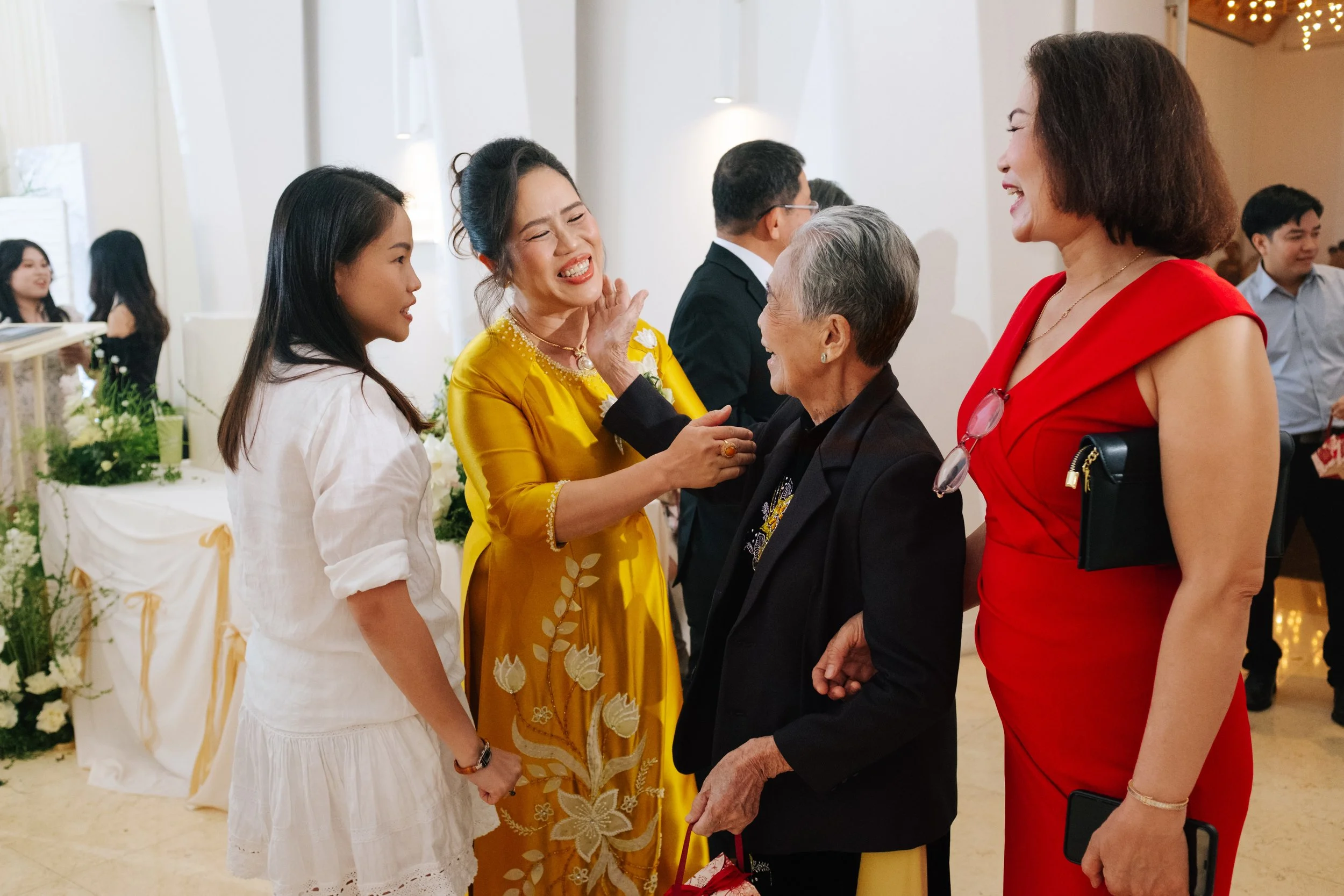 Group of women and elderly woman engaging in conversation at a celebration, with cheerful expressions.