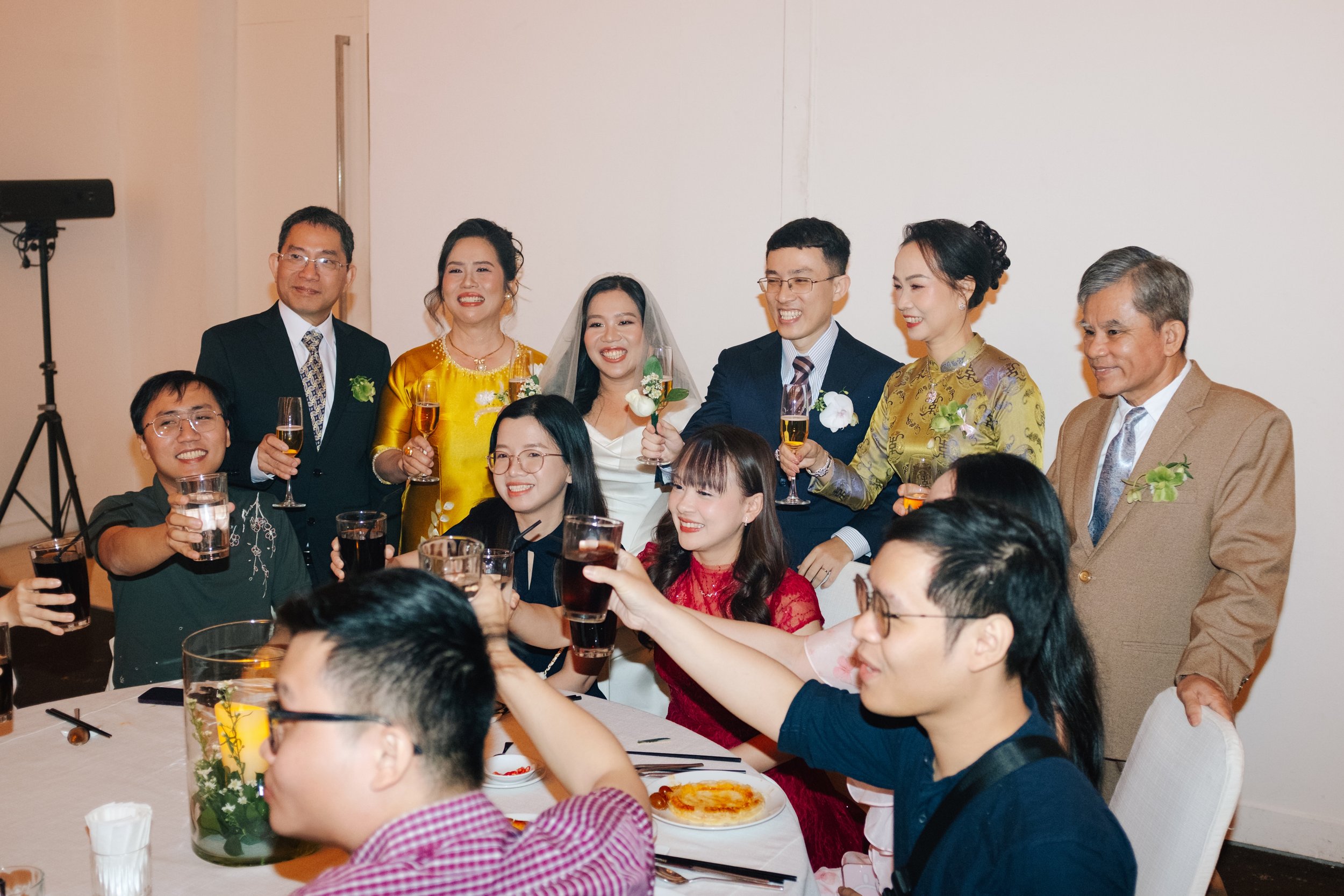 A group of friends and family celebrating at a dinner party, raising glasses of drinks together, in a festive and joyful atmosphere.