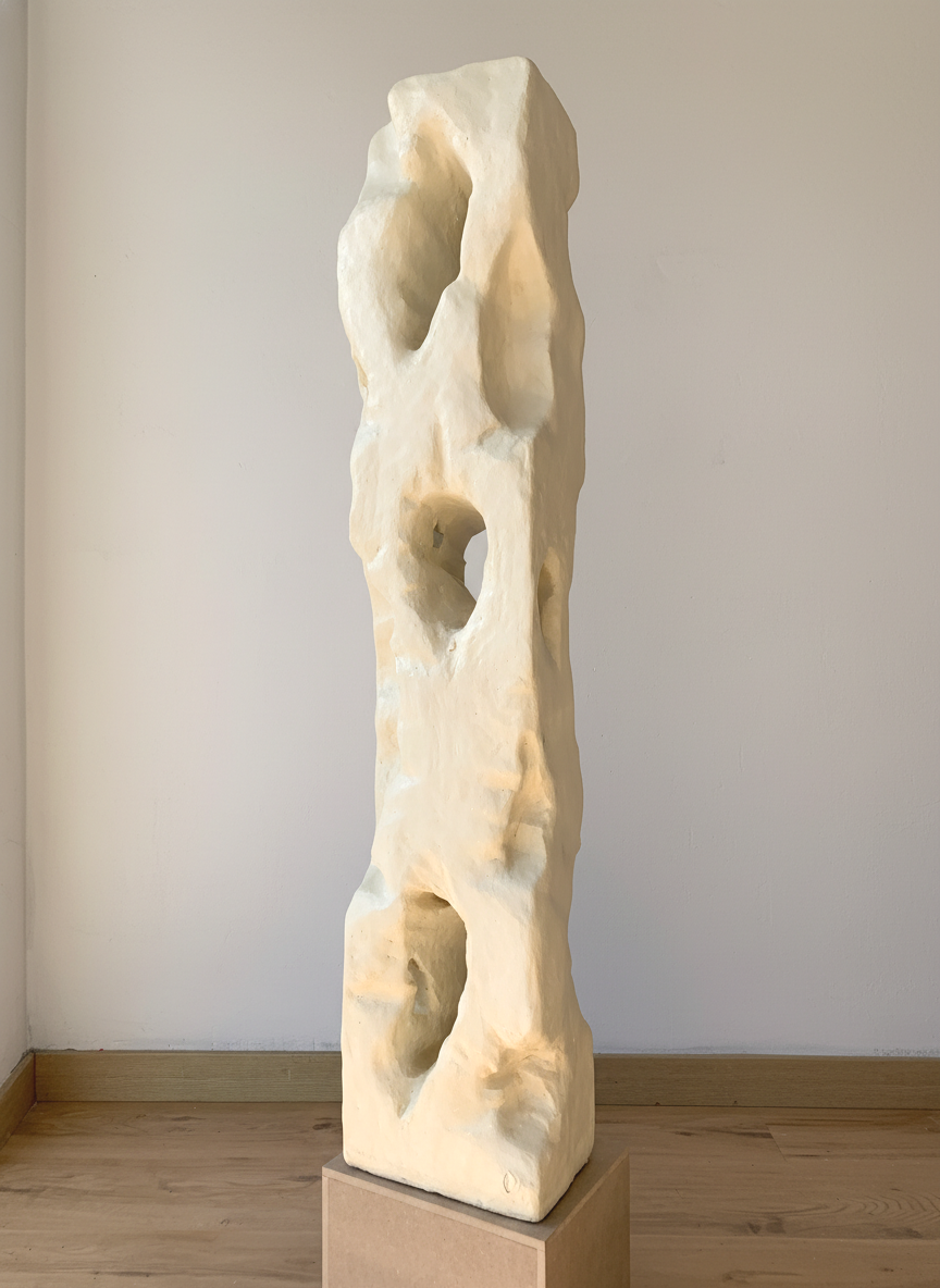 Colección Vestigio. MarcelaOnce. Arte exclusivo de prestigio internacional. Escultura con huecos y formas irregulares, ubicada sobre un pedestal de madera en una sala con paredes blancas.