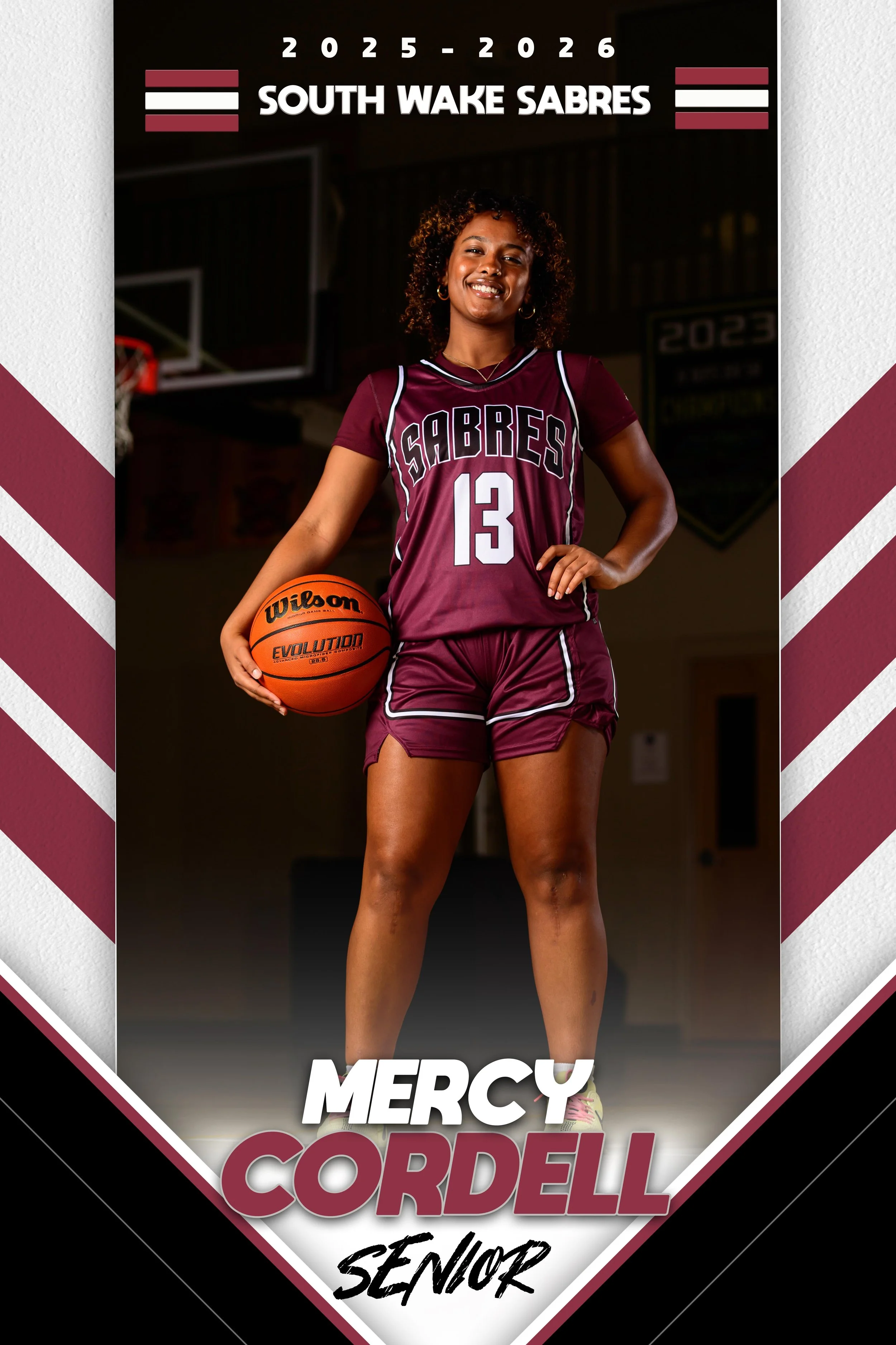 A young female basketball player in a maroon jersey and shorts holding a basketball, standing inside a gymnasium, with the text 'Mercy Cordell Senior' and 'South Wake Sabres' on a poster.