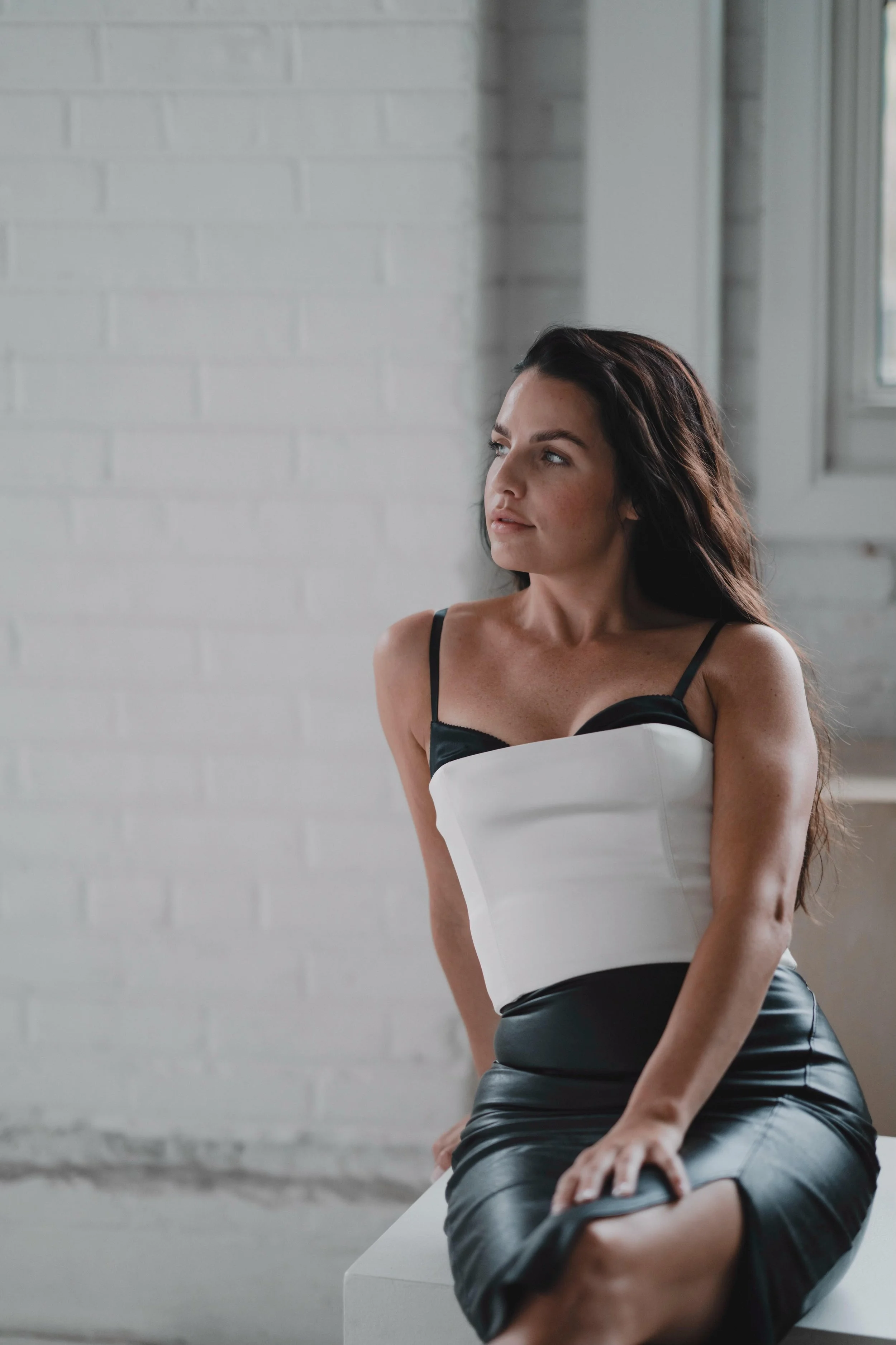 Hair stylist with dark hair sitting and looking into the distance