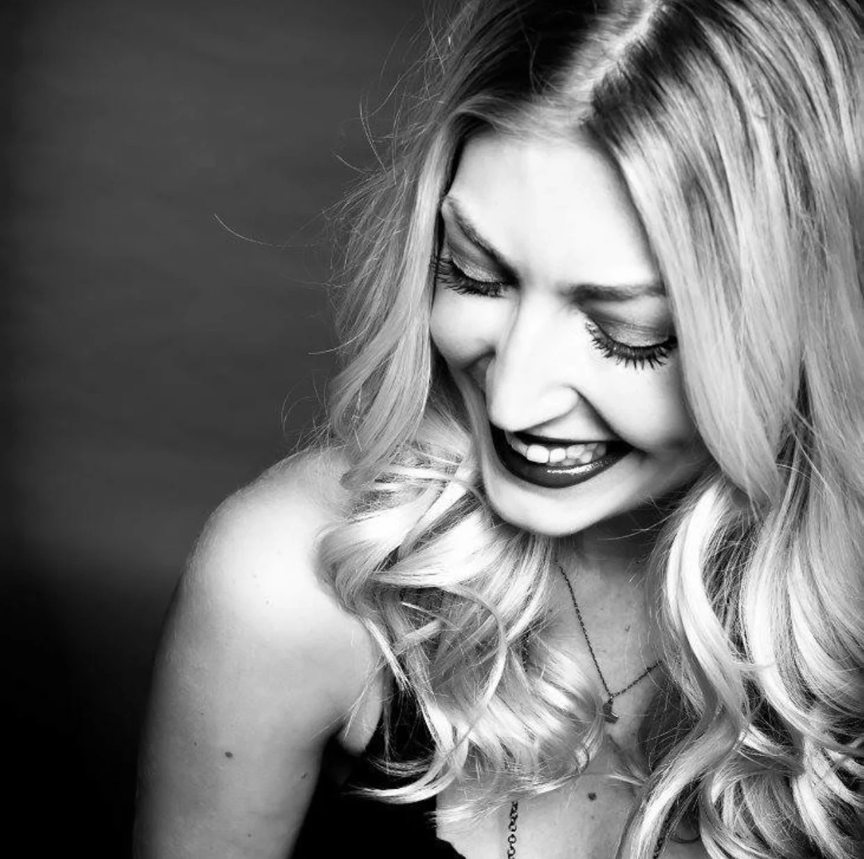 A blonde woman with short hair sits in a hair salon chair looking away from the camera 
