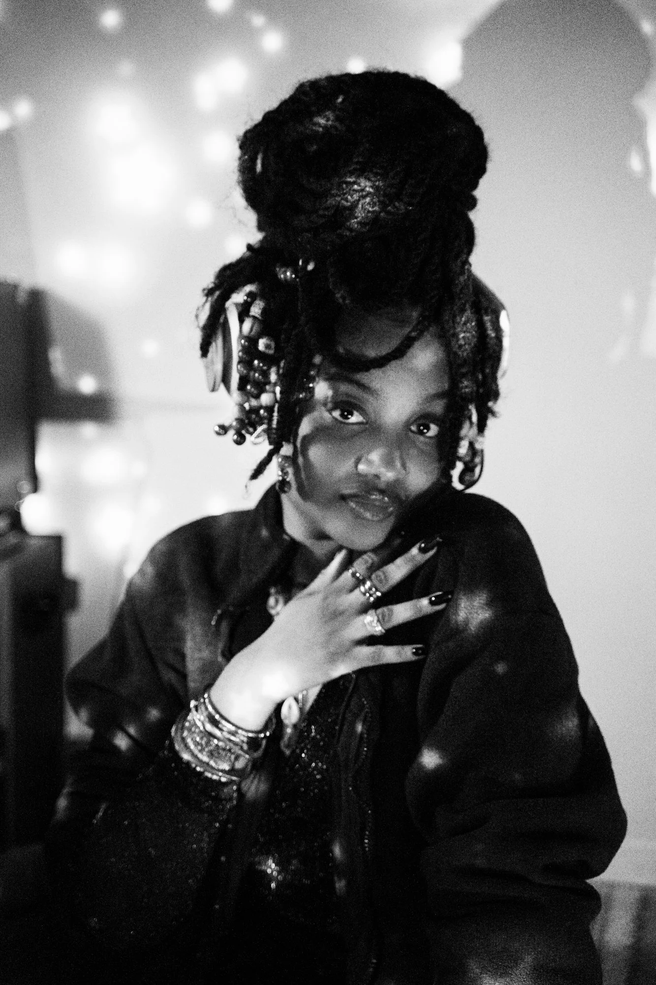 Woman, black and white, hair beads, bangles, with hand laid on shoulder, stars on woman and background.