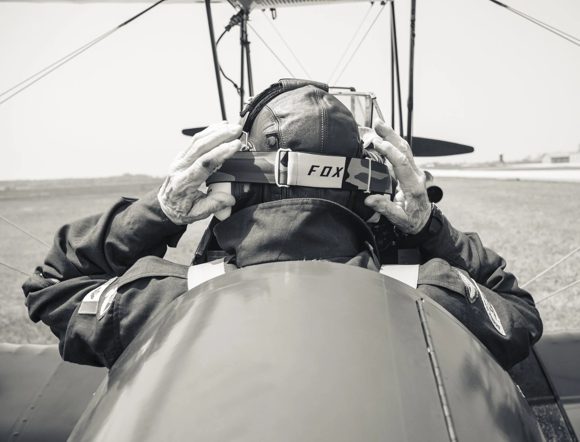 Back of pilot’s head, putting on goggles, in cockpit of WW2 training plane
